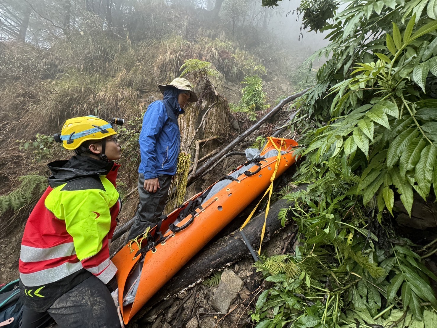 女山友不慎在白雪村墜崖，警消輪流揹負搬運遺體下山。（竹崎警分局提供）