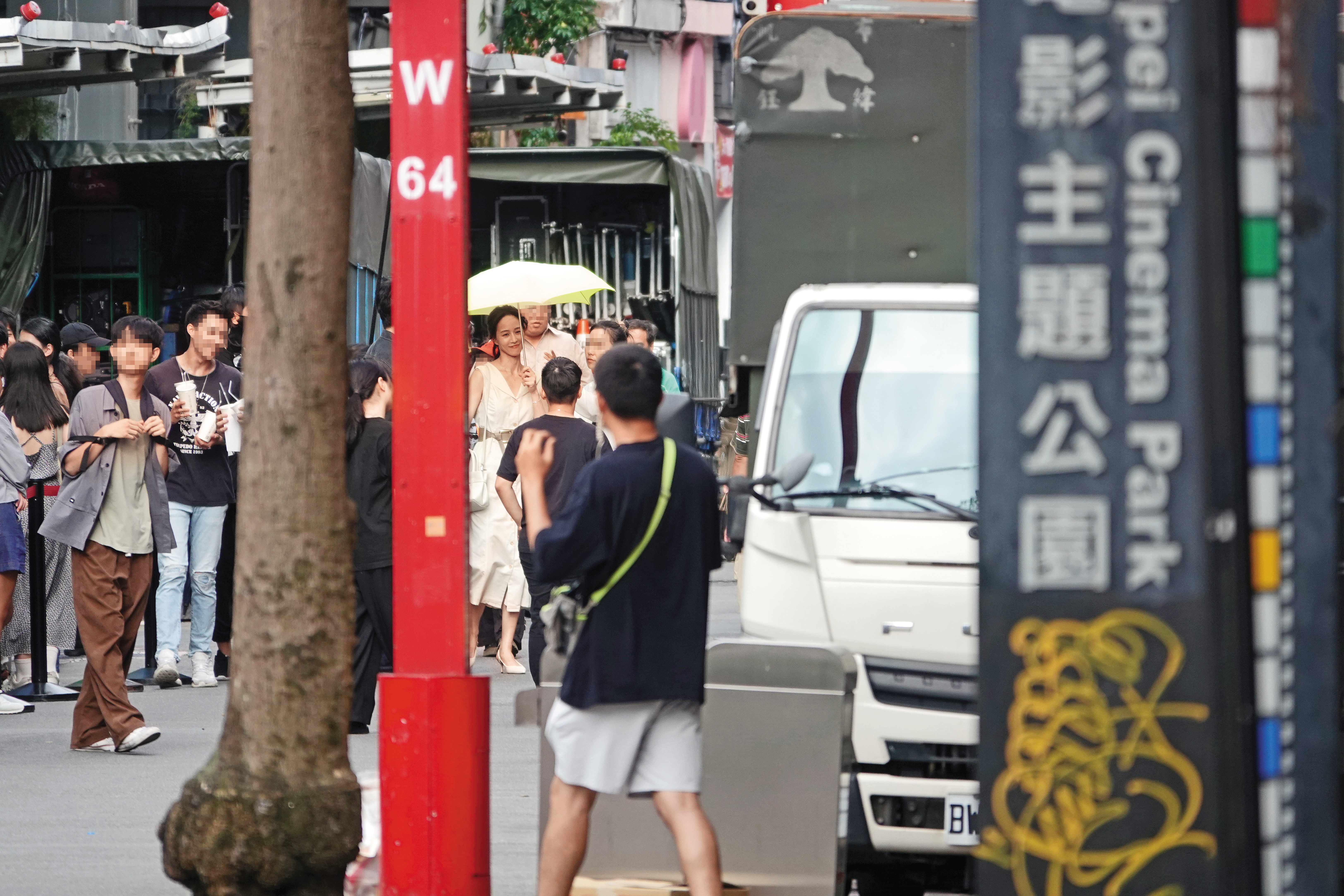 8/12 15：27 撐著傘的張鈞甯與周渝民對戲，現場一喊卡，助理趕忙上前梳化、補妝外加擦臉，張鈞甯笑得很開心。