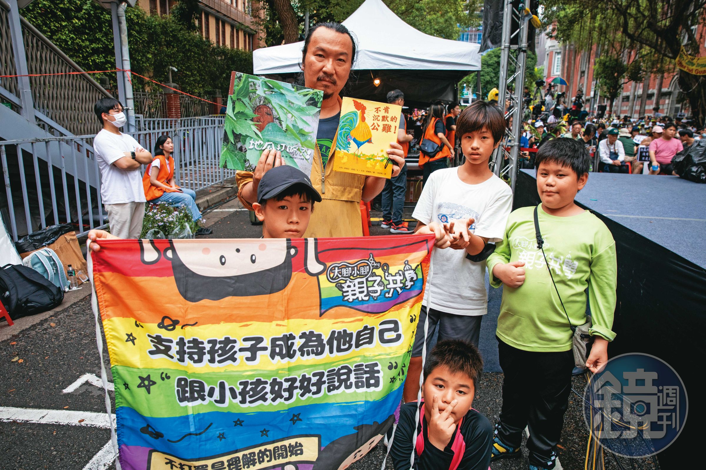 林壯穎和一群共學團的孩子，在青島東路主舞台旁合照，手裡拿的是剛在台上朗讀過的繪本。