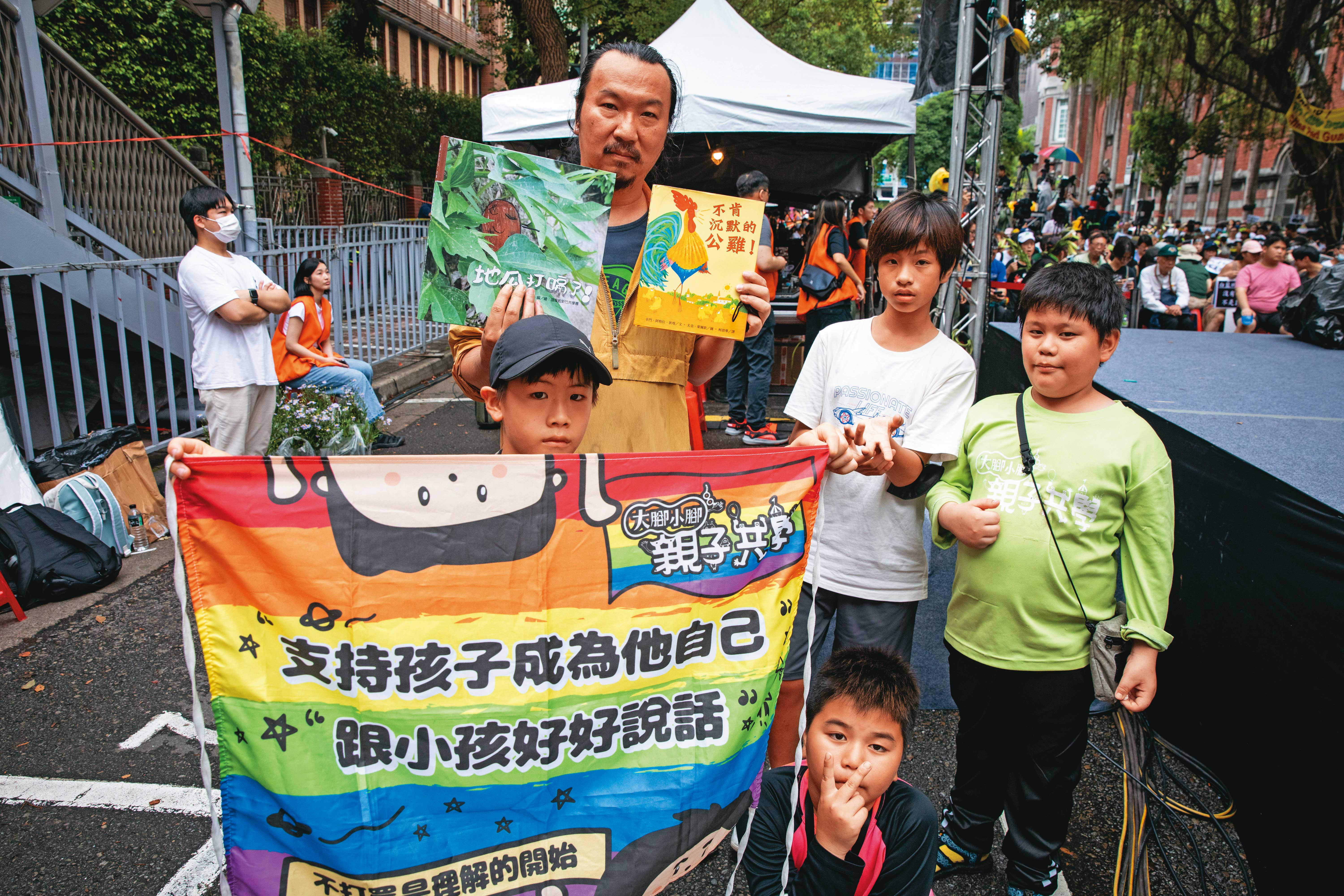 林壯穎和一群共學團的孩子，在青島東路主舞台旁合照，手裡拿的是剛在台上朗讀過的繪本。