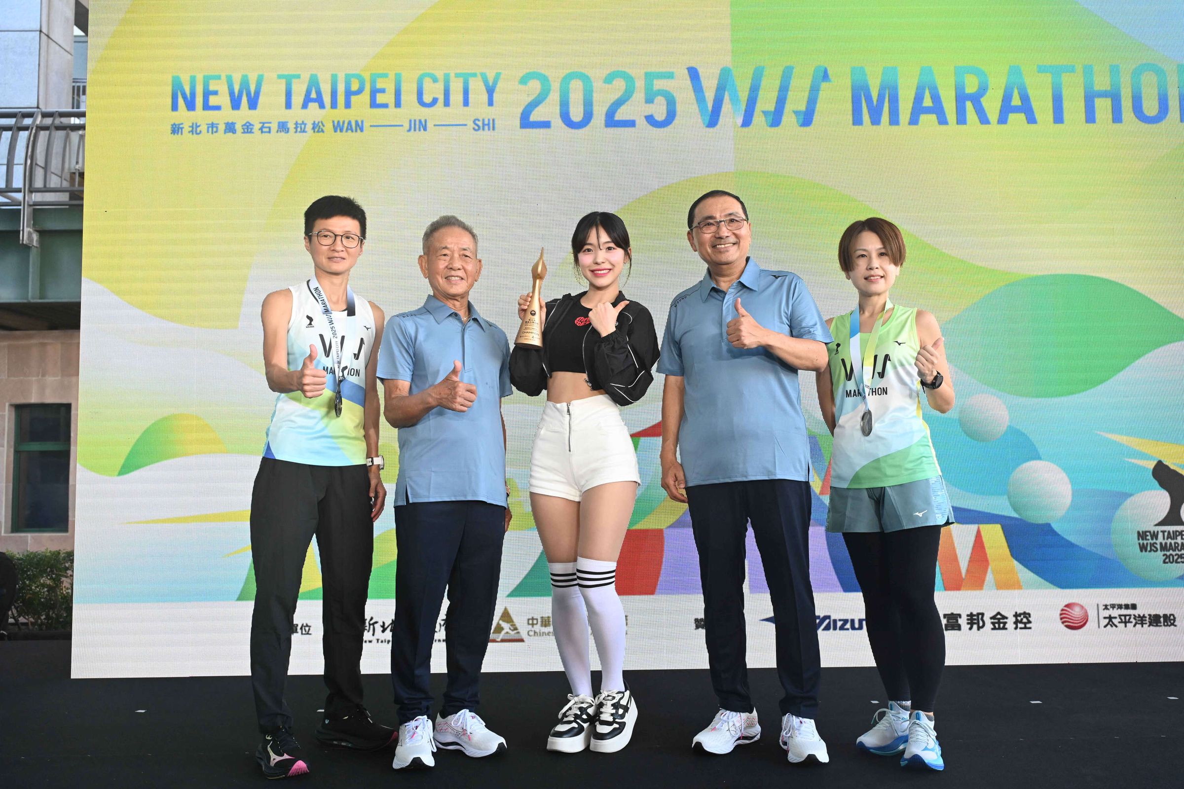 李多慧（中）及跑者一同展示紀念跑衣、完賽獎牌及火炬流線形獎盃。（新北市政府提供）