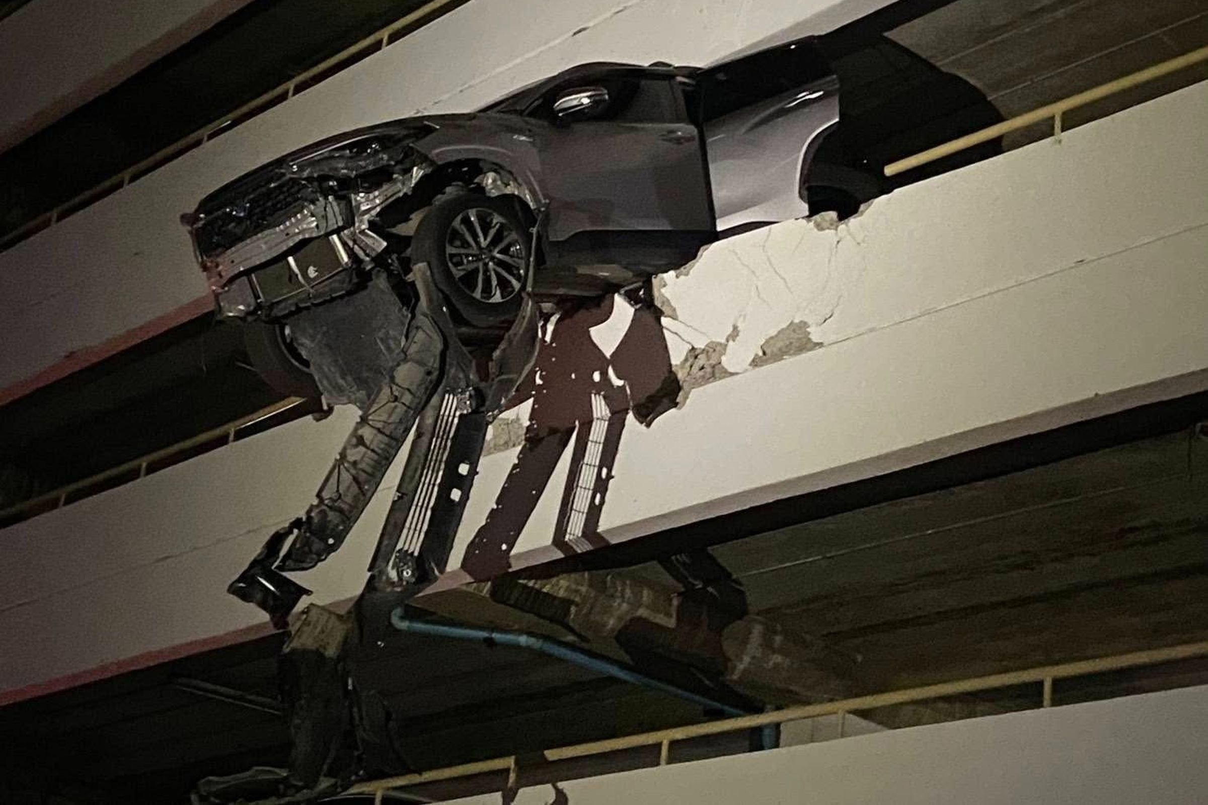 1輛休旅車失控衝破外牆,車頭懸空掛在樓層邊緣,整輛車搖搖欲墜。(翻攝自Sittipon Benz FB)