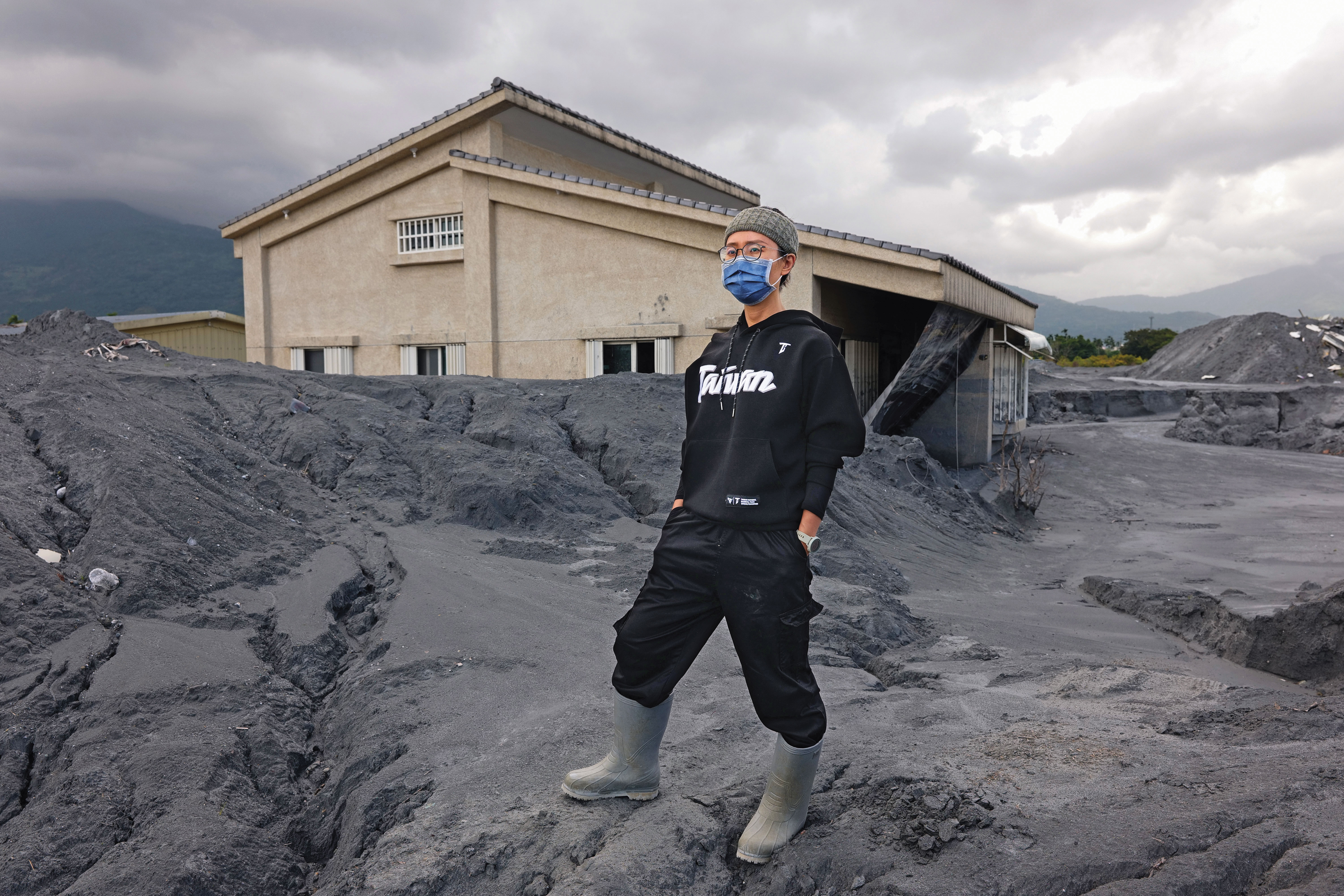 康康站在被土堆淹沒的母親家前。