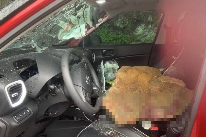 石塊從山壁墜落，直接擊中一輛紅色休旅車的前擋風玻璃。（翻攝畫面）