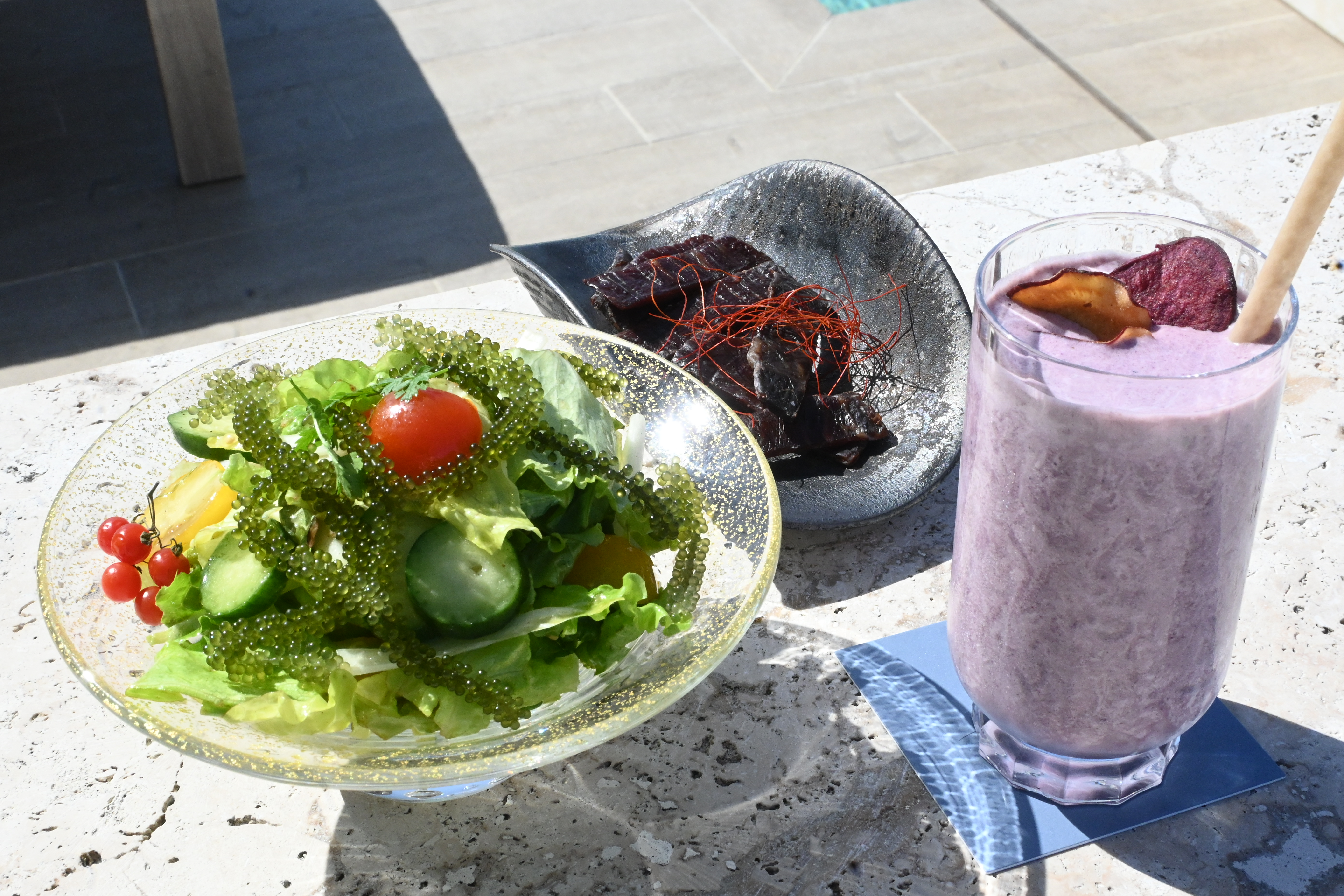 以宮古島紫薯為基底，搭配黑芝麻與香蕉調製而成的「Purple Yam Smoothie」（右，日幣2,000元／份，約NT$379）搭配短角和牛肉乾「Shorthorn Wagyu Beef Jerky」（中，日幣3,800元／份，約NT$720）與海葡萄沙拉「Green Caviar Salad」（左，日幣2,500元／份，約NT$474）這一套午茶組合，甜鹹鮮都有了。
