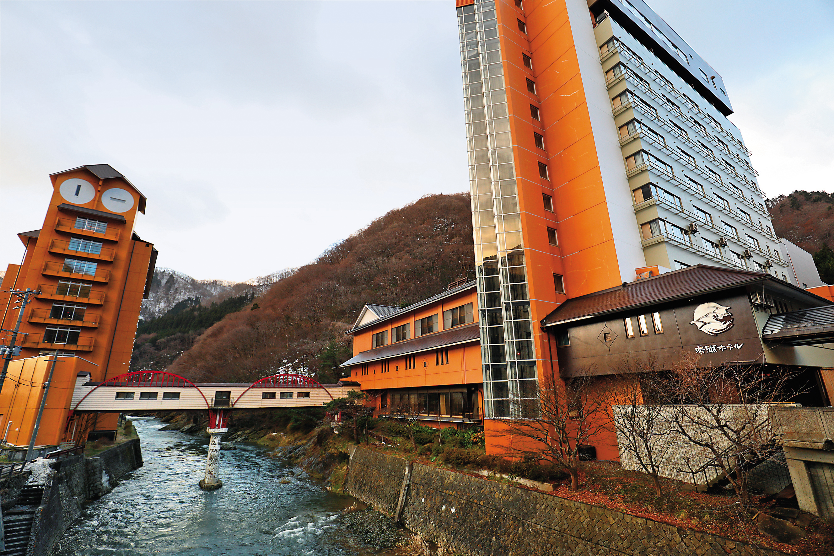 「湯瀨溫泉Yuze Hotel」以一座跨越米代川的紅橋連接新館與舊館。