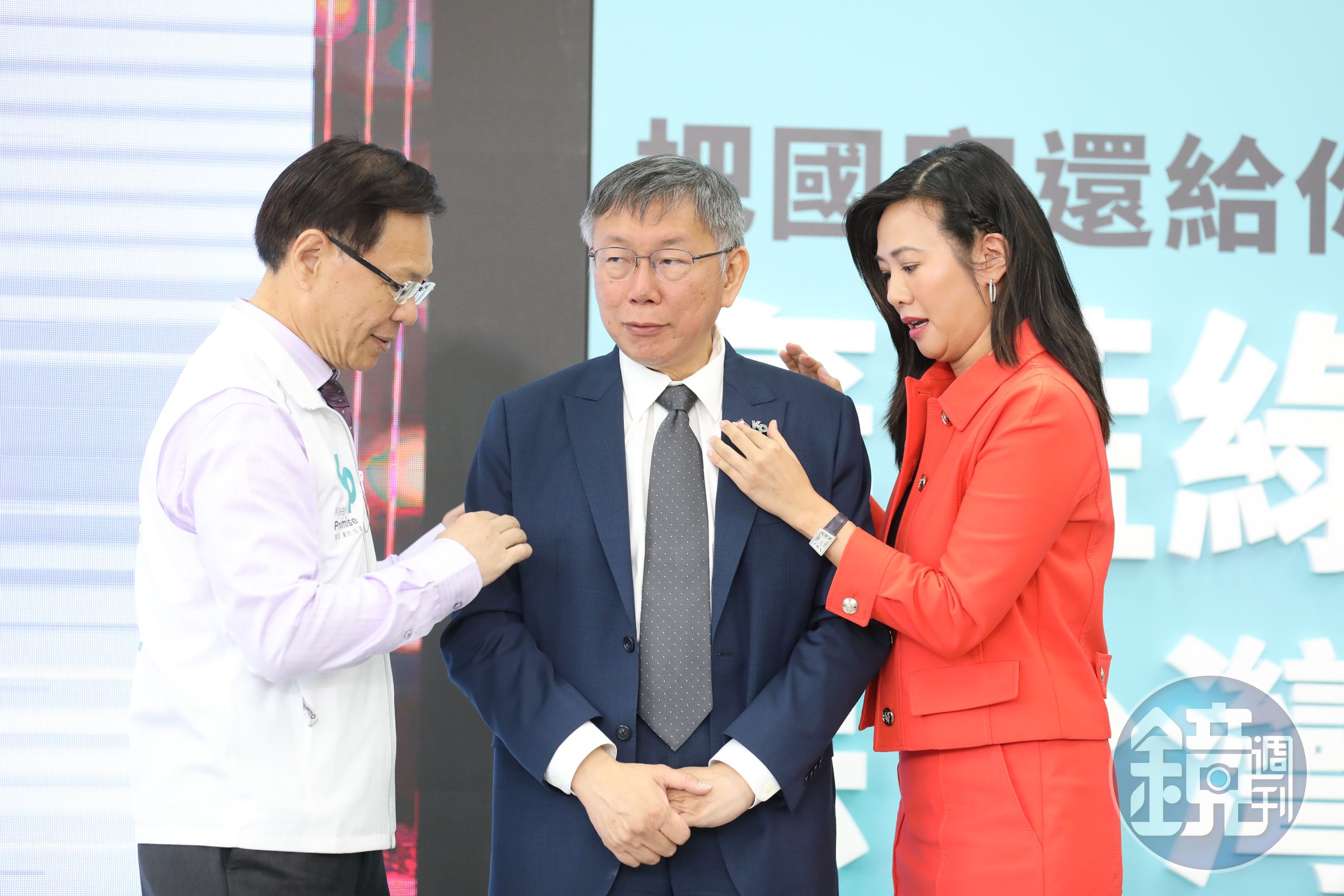 柯文哲（中）開金融政見記者會，吳欣盈（右）幫他喬徽章。