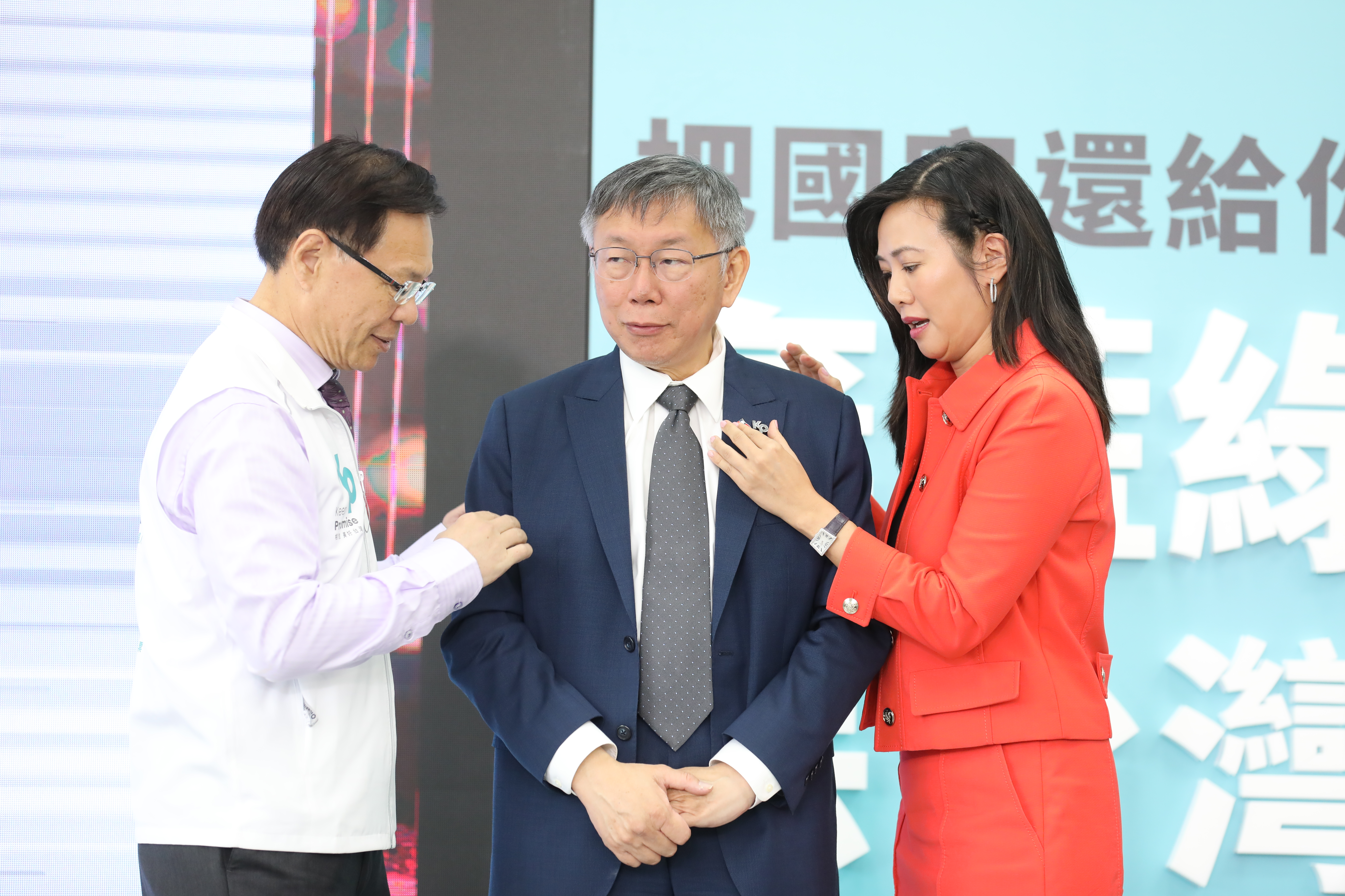 柯文哲（中）開金融政見記者會，吳欣盈（右）幫他喬徽章。