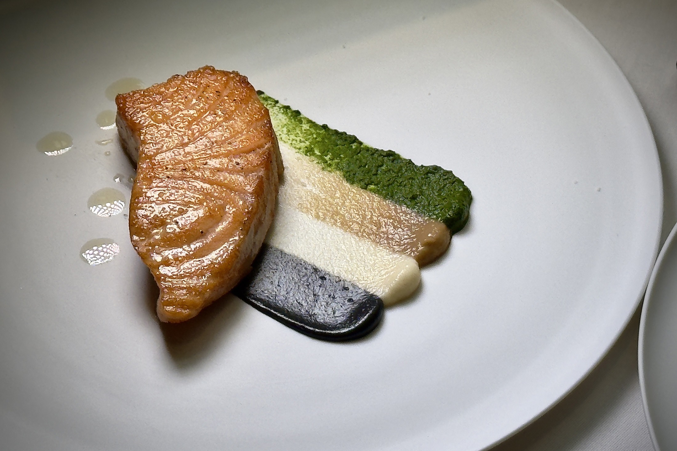 熱前菜「爐烤挪威鮭魚」或盤飾融入海洋拉娜品牌色彩，將馬鈴薯泥以竹炭蒜香巴薩米克醋（曜黑）、白花菜（乳白）、咖啡洋蔥（珍珠白）、松子皇宮菜（碧綠）創意呈現搶眼視覺驚豔。