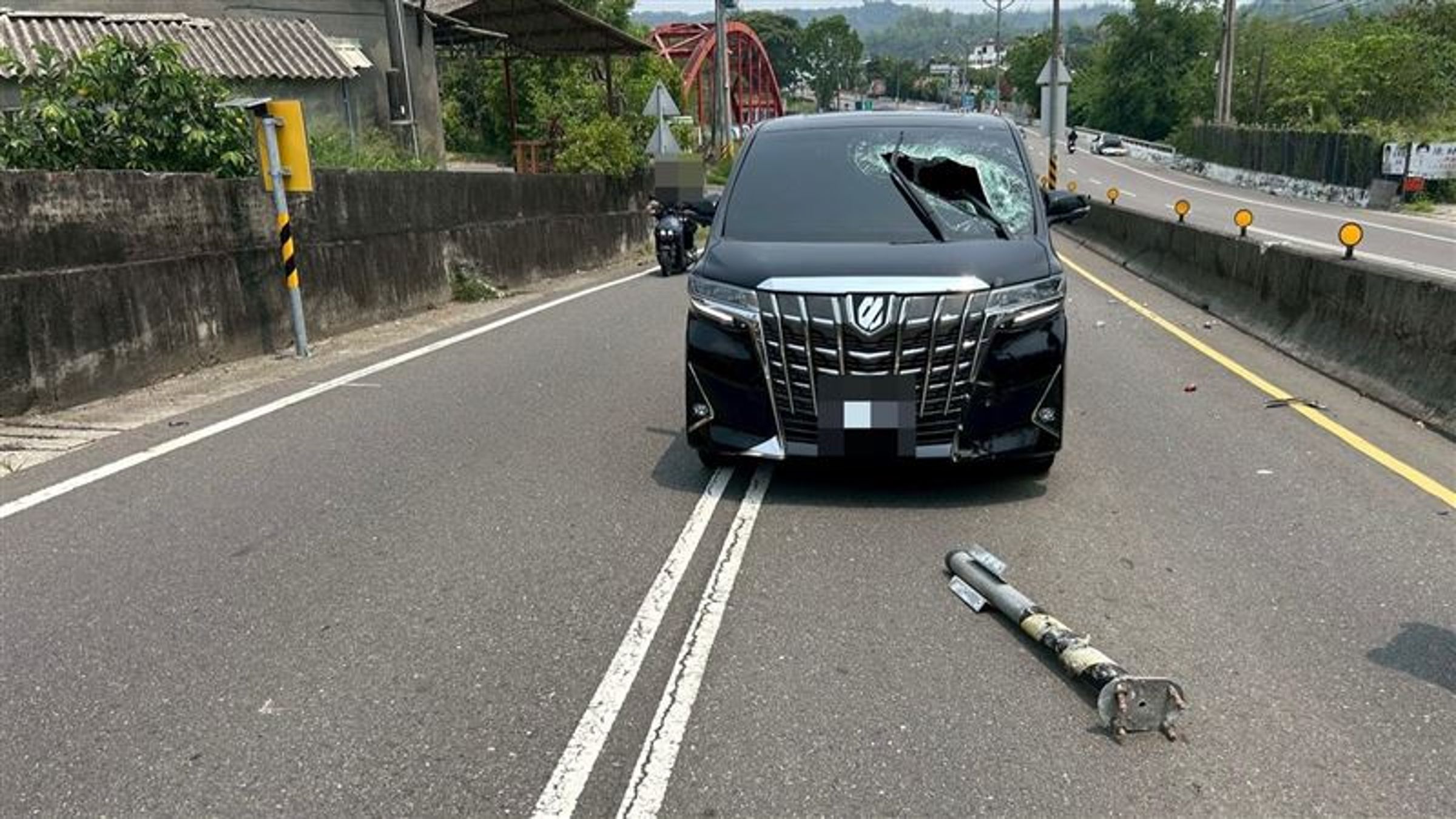 斷裂的標誌桿噴飛至對向車道,精準砸中俗稱「運兵車」的Alphard休旅車,造成擋風玻璃大面積破碎。(翻攝畫面)