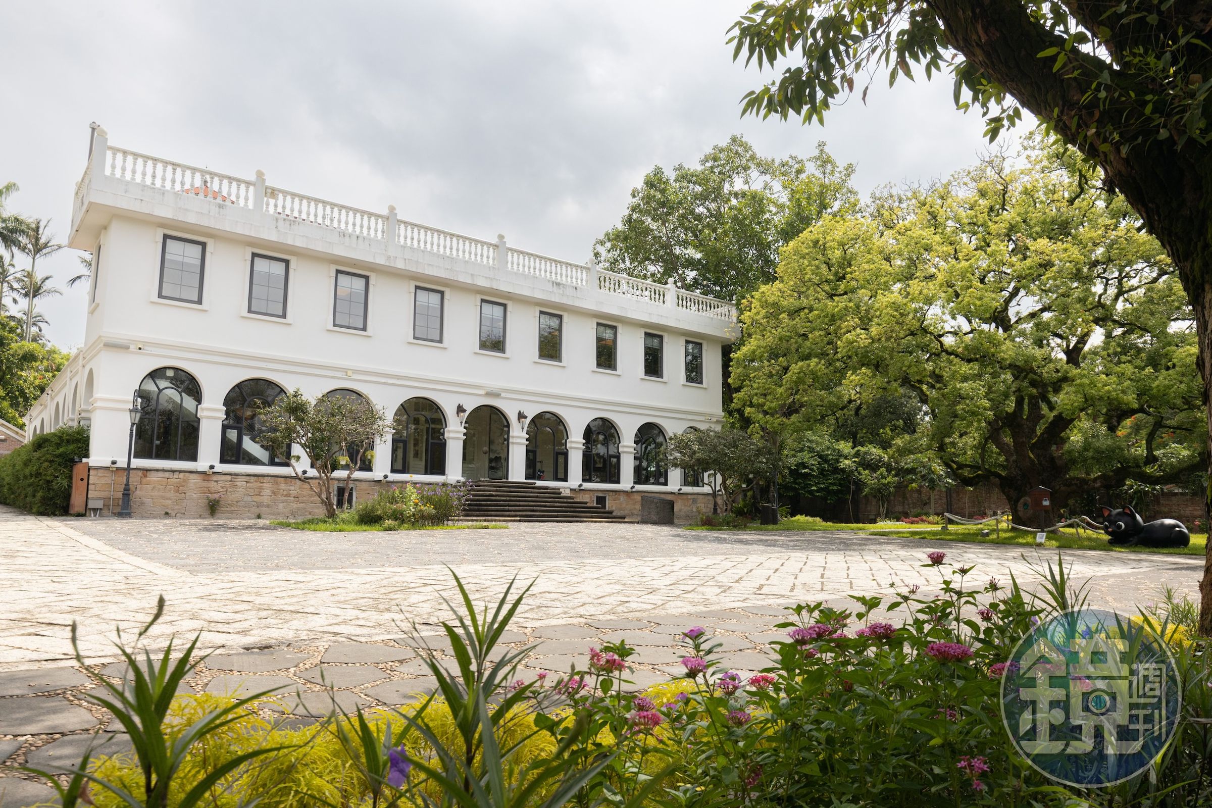 巫登益美術館所在的淡水歷史建物園區教士會館,是由馬偕博士於1875年親自督建,主建築的歐式白堊洋樓,與百年樟樹相映成趣。