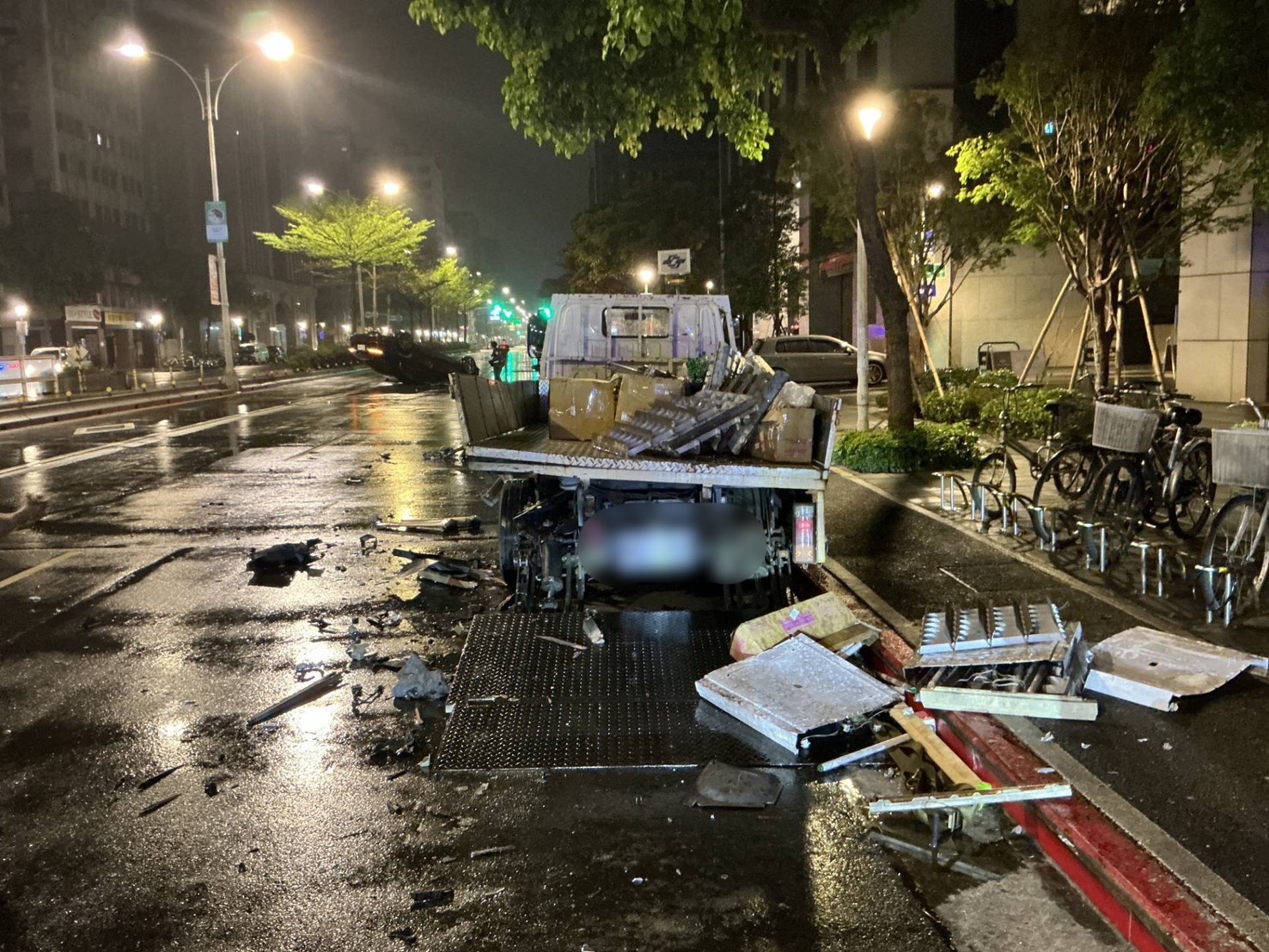 黑色賓士撞上路旁大型工程車，工程車上鐵物物品被撞落，散落在地上。（翻攝畫面）