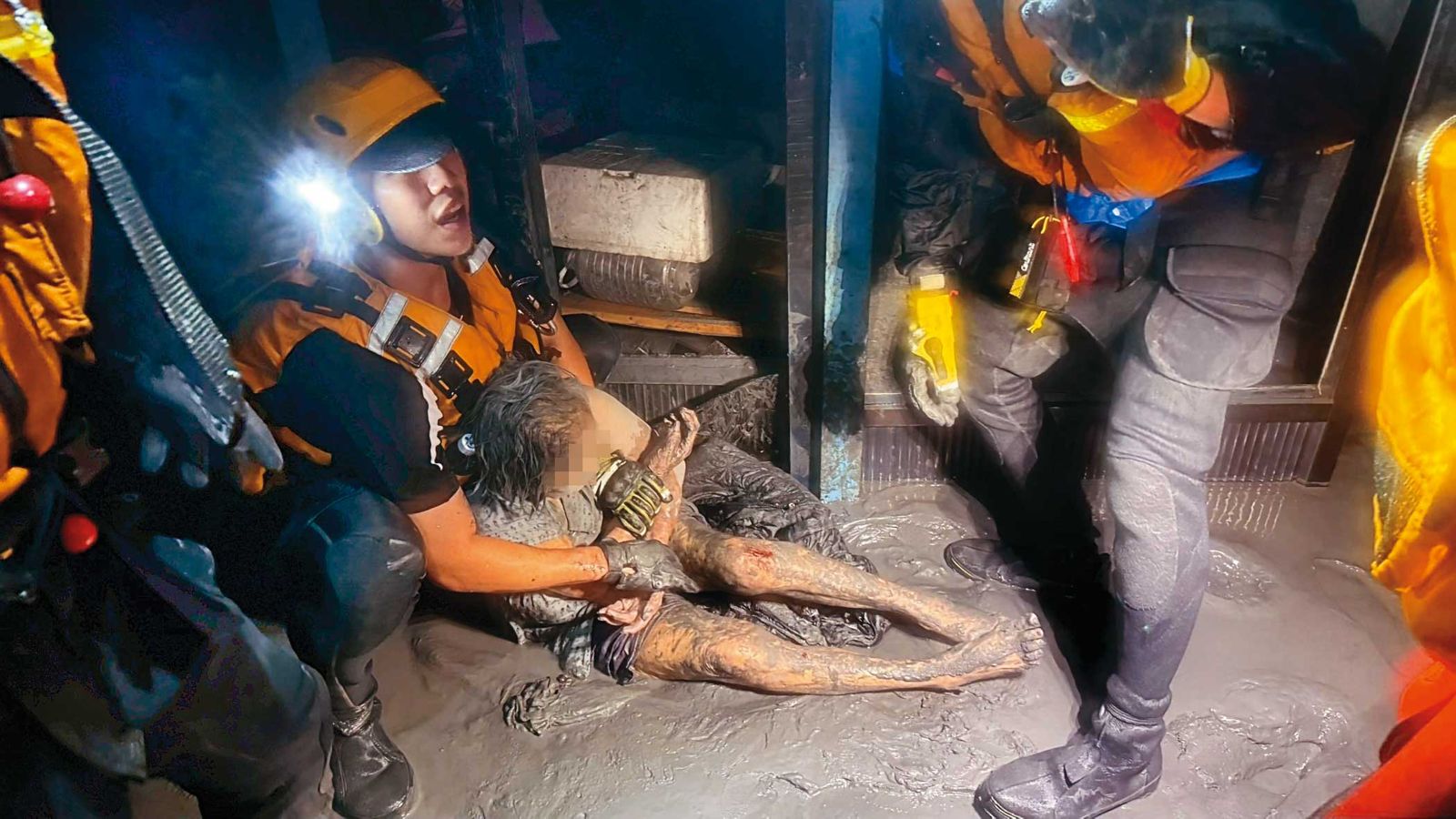 搜救人員進入民宅搜救，一名受困民眾被找到時滿身泥濘。（中央災害應變中心提供）