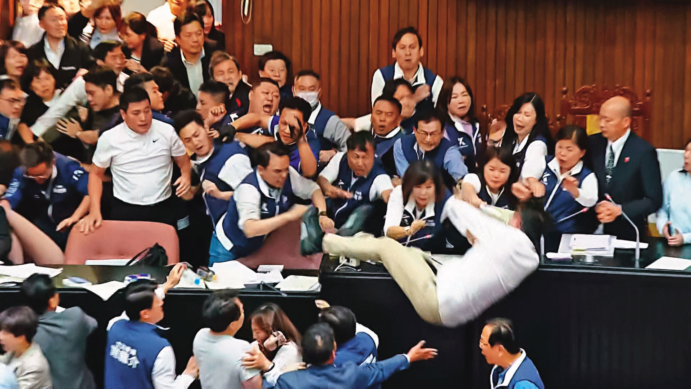 民進黨從正面進攻主席台,多人因此摔傷。圖為沈伯洋從主席台摔落。(翻攝鏡新聞)