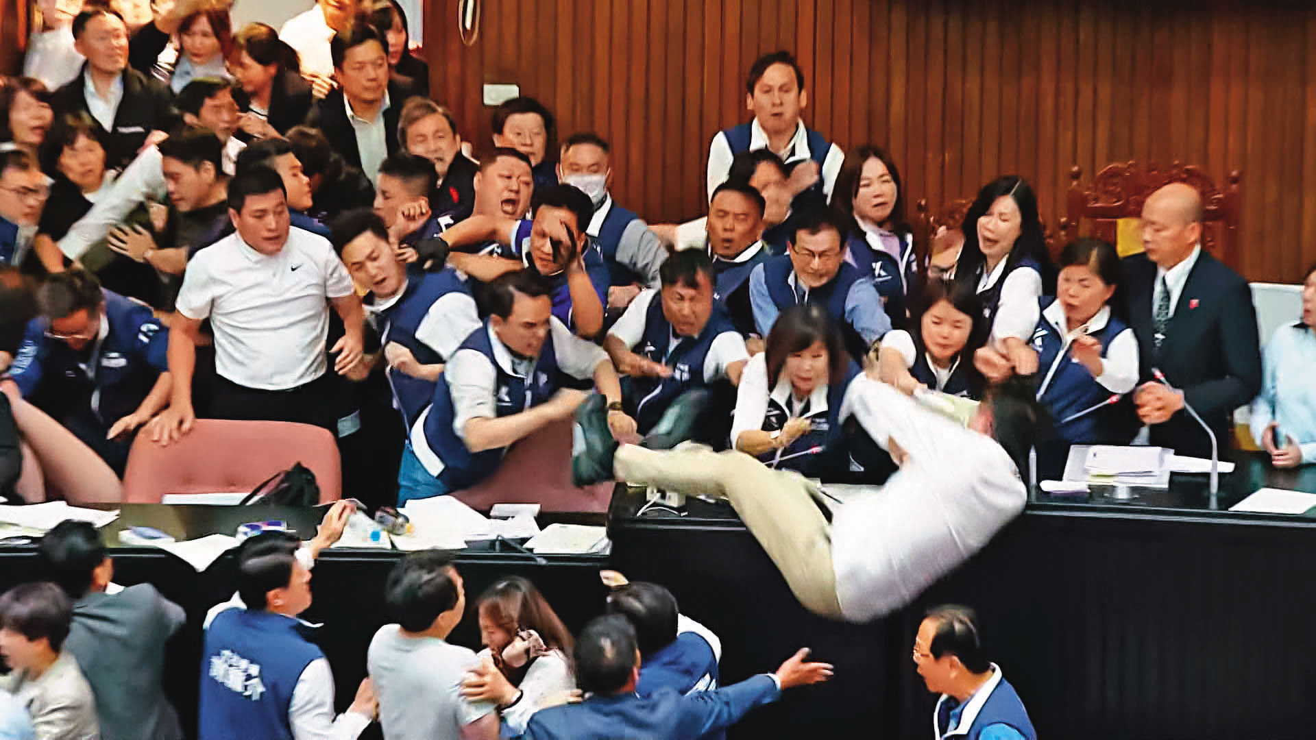 民進黨從正面進攻主席台,多人因此摔傷。圖為沈伯洋從主席台摔落。(翻攝鏡新聞)