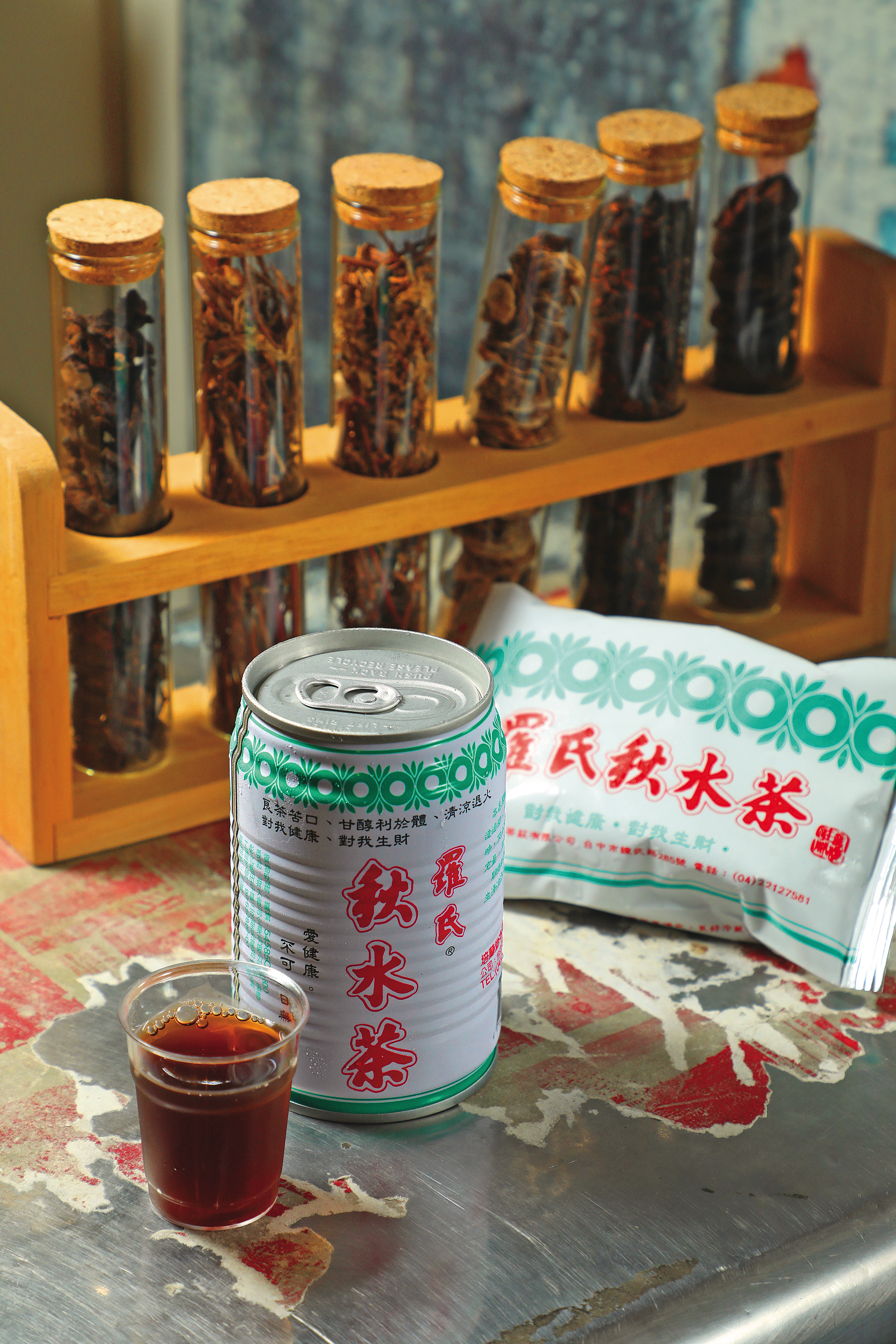 鋁箔包（後，26元／包）與易開罐（前，34元／瓶）的羅氏秋水茶，因為用的糖不同而有味道上的些微差異。