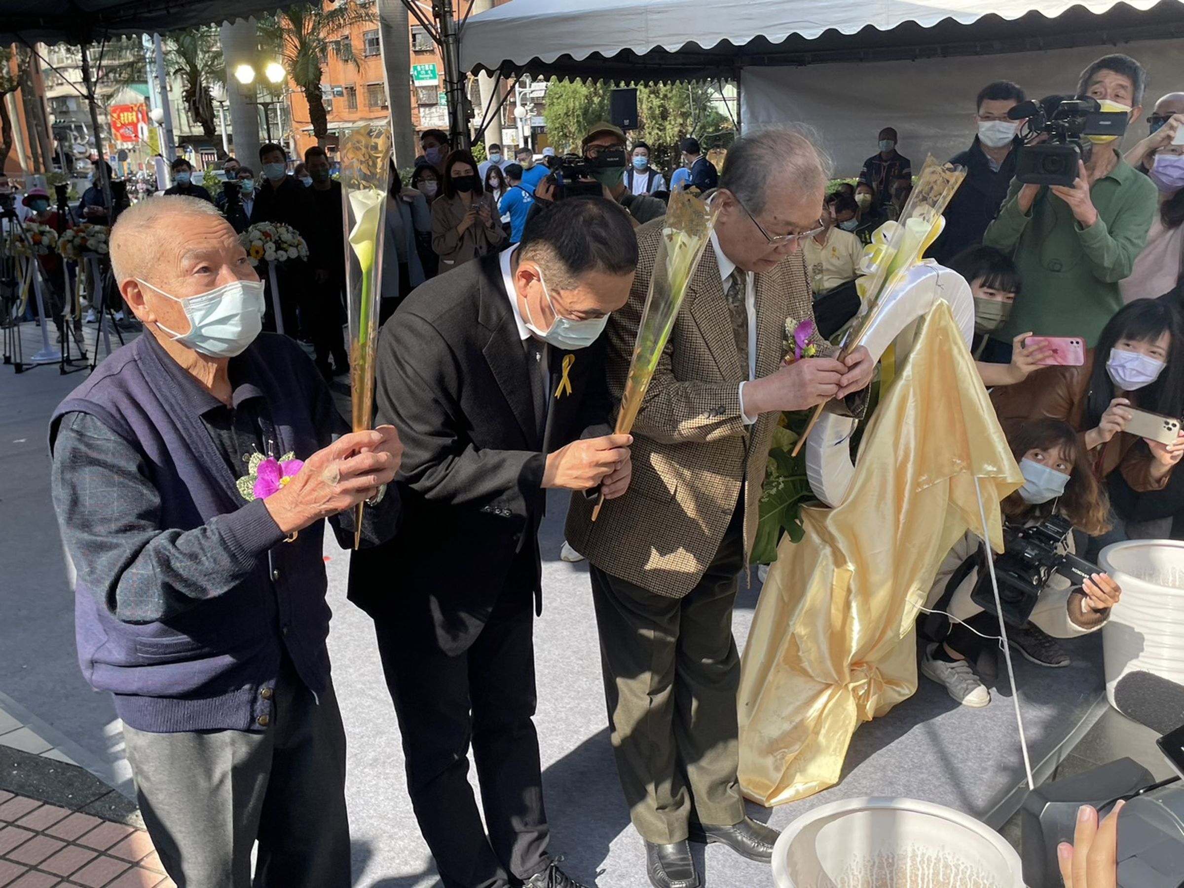 今年在三重228和平紀念公園舉行的228紀念儀式,趙水濱(左)與市長侯友宜及新北市228總會理事長洪顯詔(右)手執鮮花於紀念碑前獻花。(新北民政局提供)
