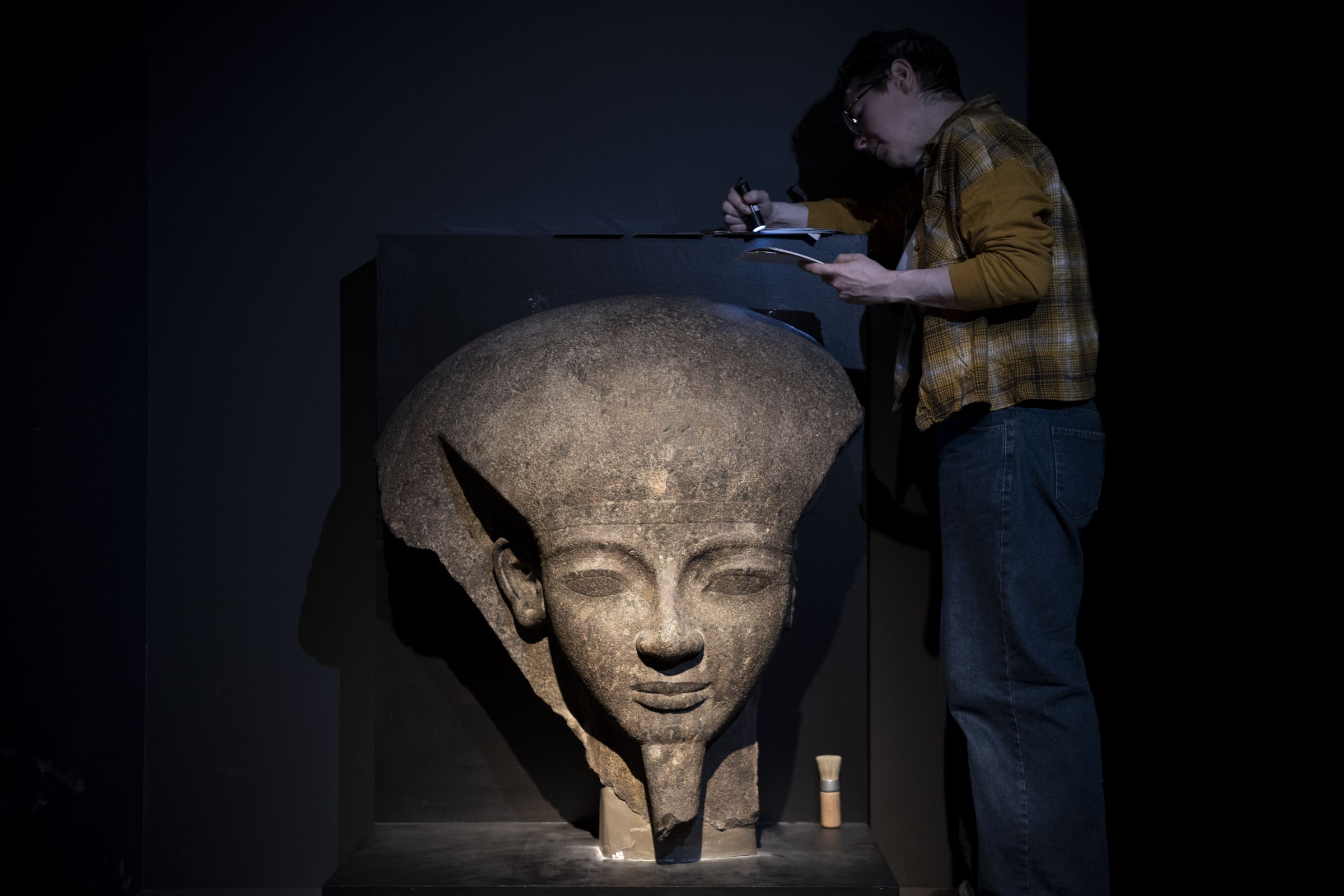 大英博物館工作人員在展出前檢視展品〈拉美西斯六世的石棺蓋殘片〉。(奇美博物館提供)