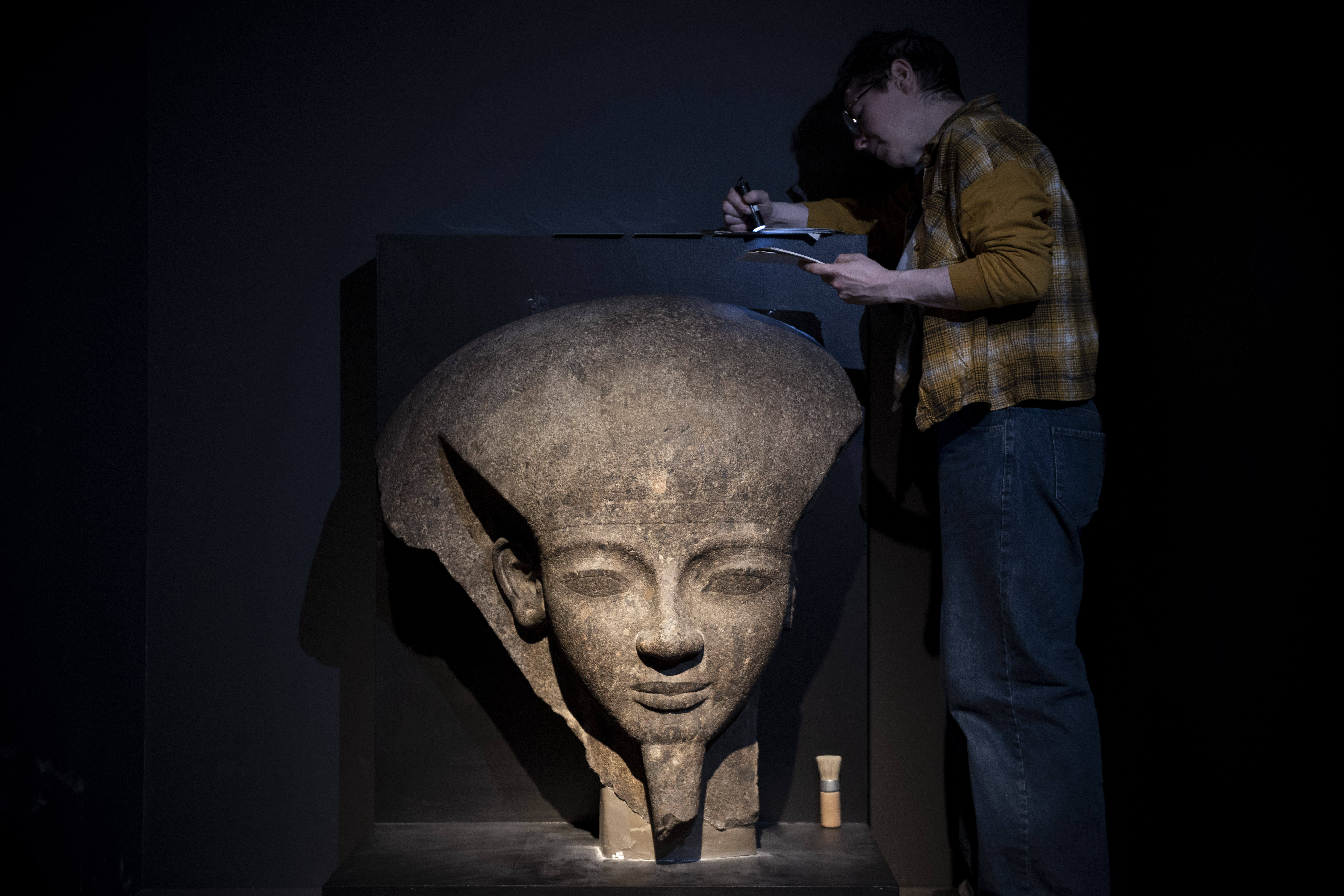 大英博物館工作人員在展出前檢視展品〈拉美西斯六世的石棺蓋殘片〉。（奇美博物館提供）