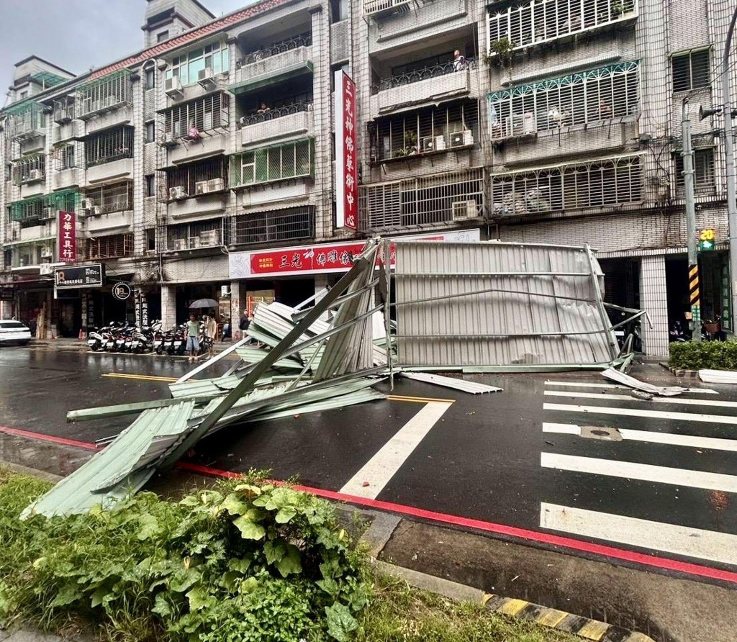 由於鐵皮屋砸落的面積太大，一度導致雙向道路無法通行。（翻攝畫面）