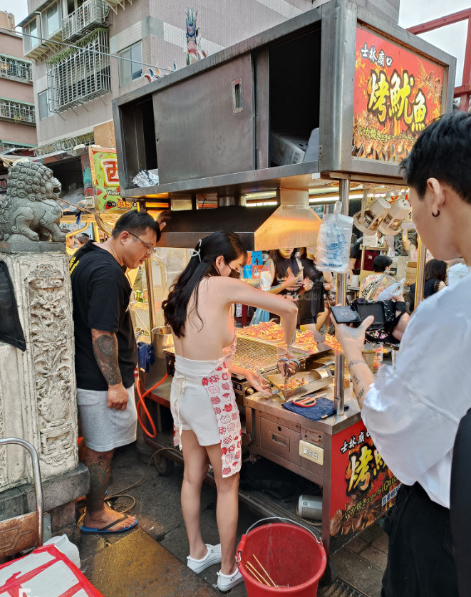 晴天只穿圍裙、熱褲在烤魷魚攤工作，側面清楚可見姣好身材全都露。（翻攝晴天臉書）