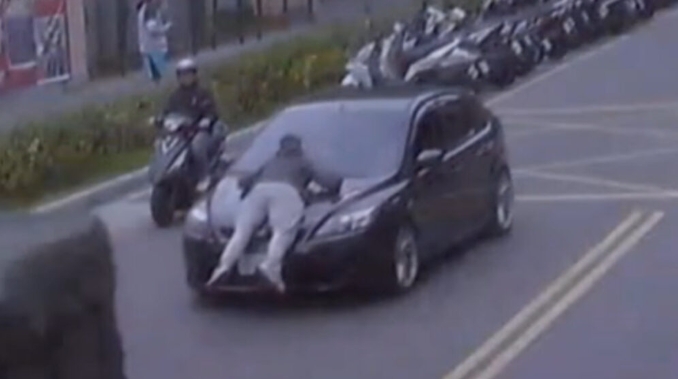 向男不甘被分手，除了趴伏在引擎蓋上不讓杜女離開，還報復舉報對方持有毒品。（翻攝畫面）