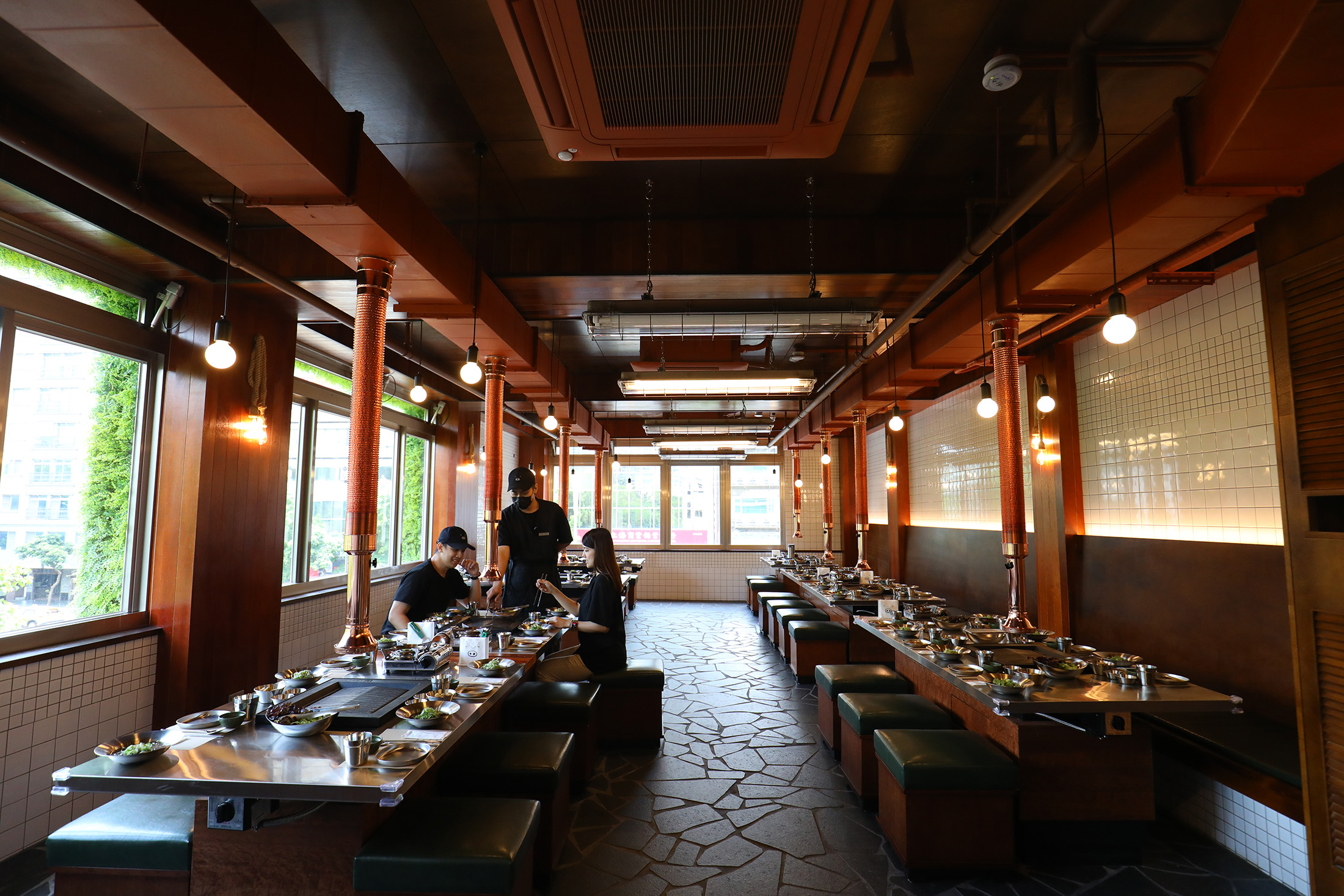 台灣「金豬食堂」整體空間設計延續首爾本店風格，營造舊時代烤肉氛圍，包括牆面白色磁磚、咖啡色底座的綠色皮面座椅。