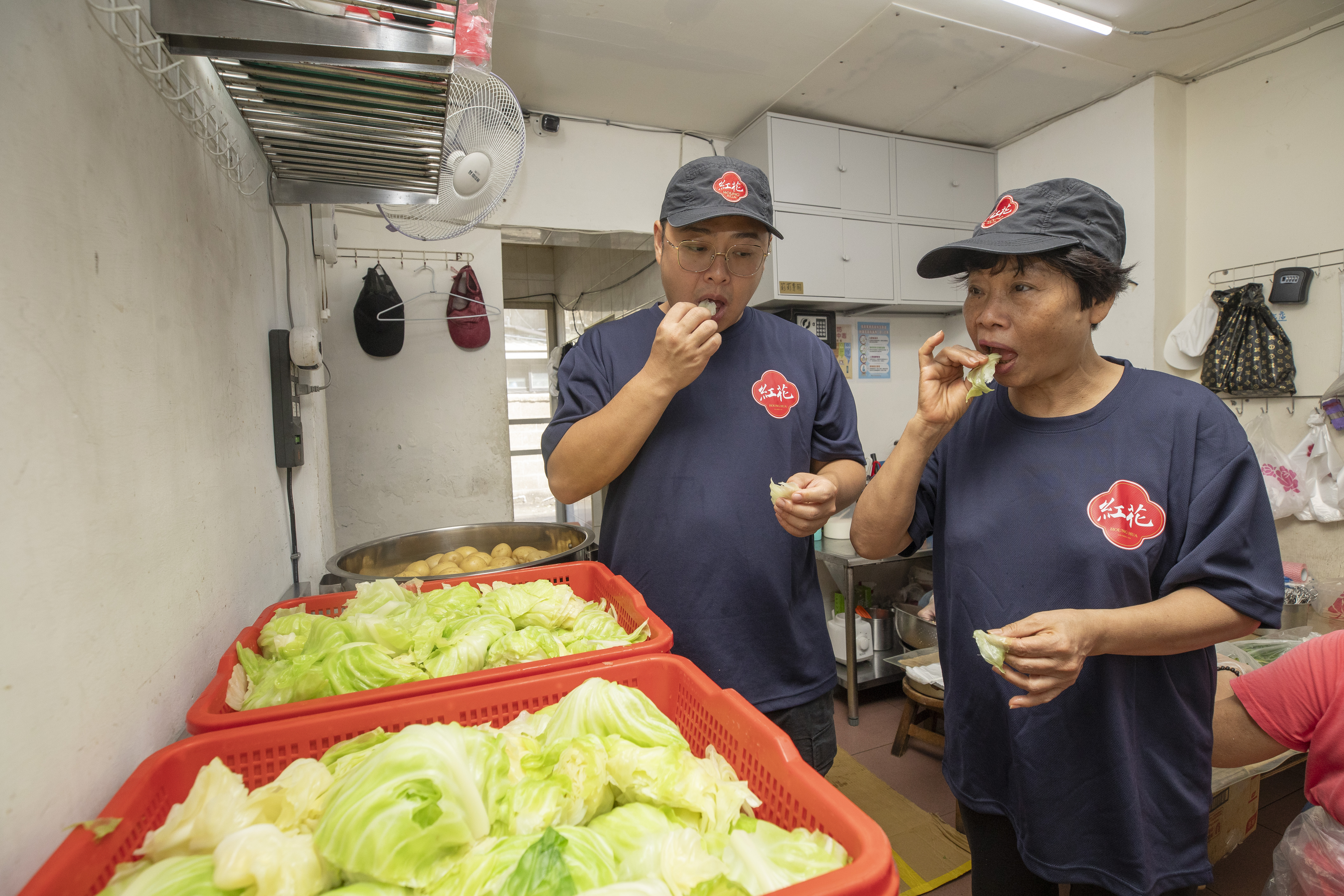 紅花的蔬菜類只需汆燙，許阿淑（右）規定兒子林震耀（左）煮完菜必須試吃，確認口感是否清脆。