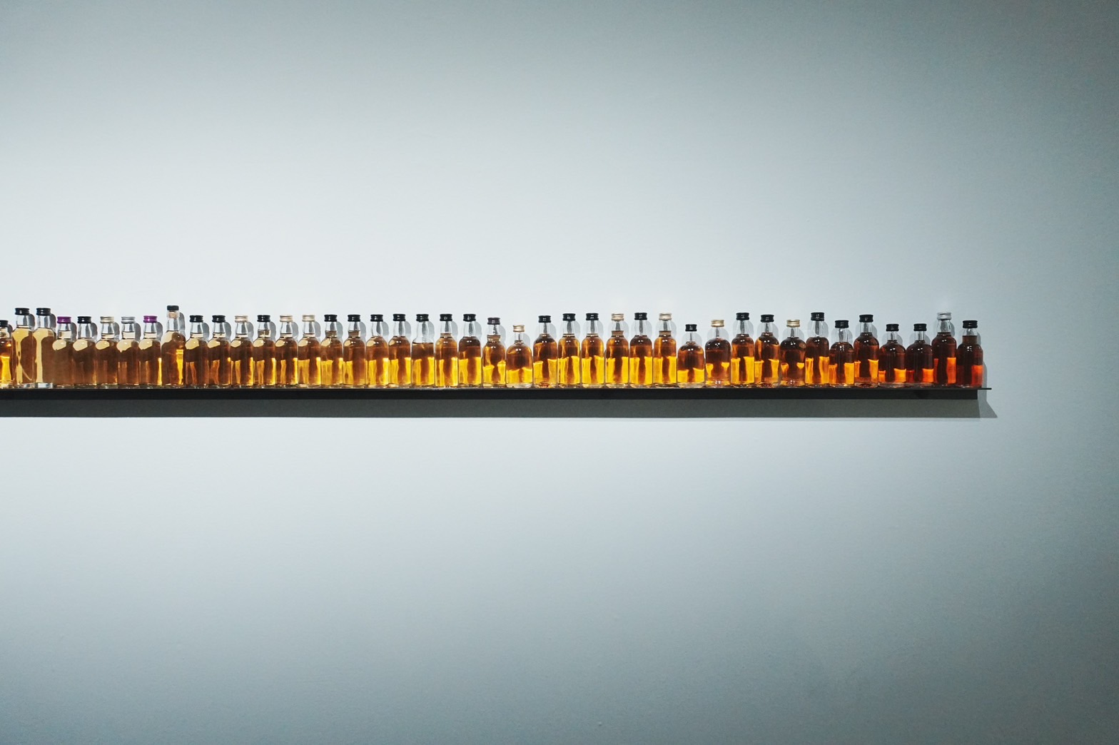 李明學的作品《Frequency》以試飲瓶排列成漸層彩象徵威士忌製程中時間的沉澱與變化，也反映出記憶中的層次與未來的無限可能性。 