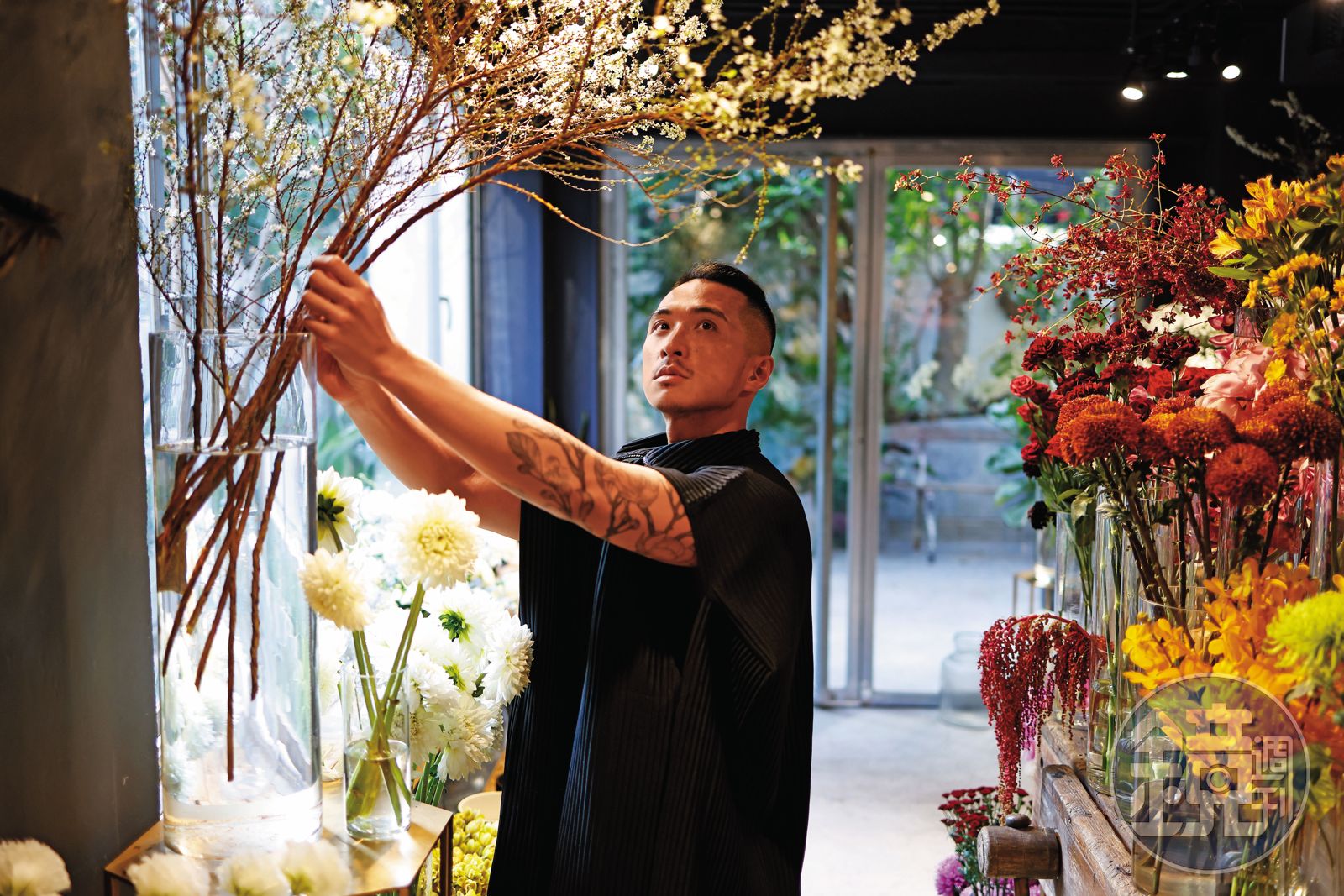 林哲瑋在自己的花店受訪，露出手臂上的刺青，其中一句是巴黎5月學運的抗爭標語：「讓想像力掌權。」（圖／鏡週刊）