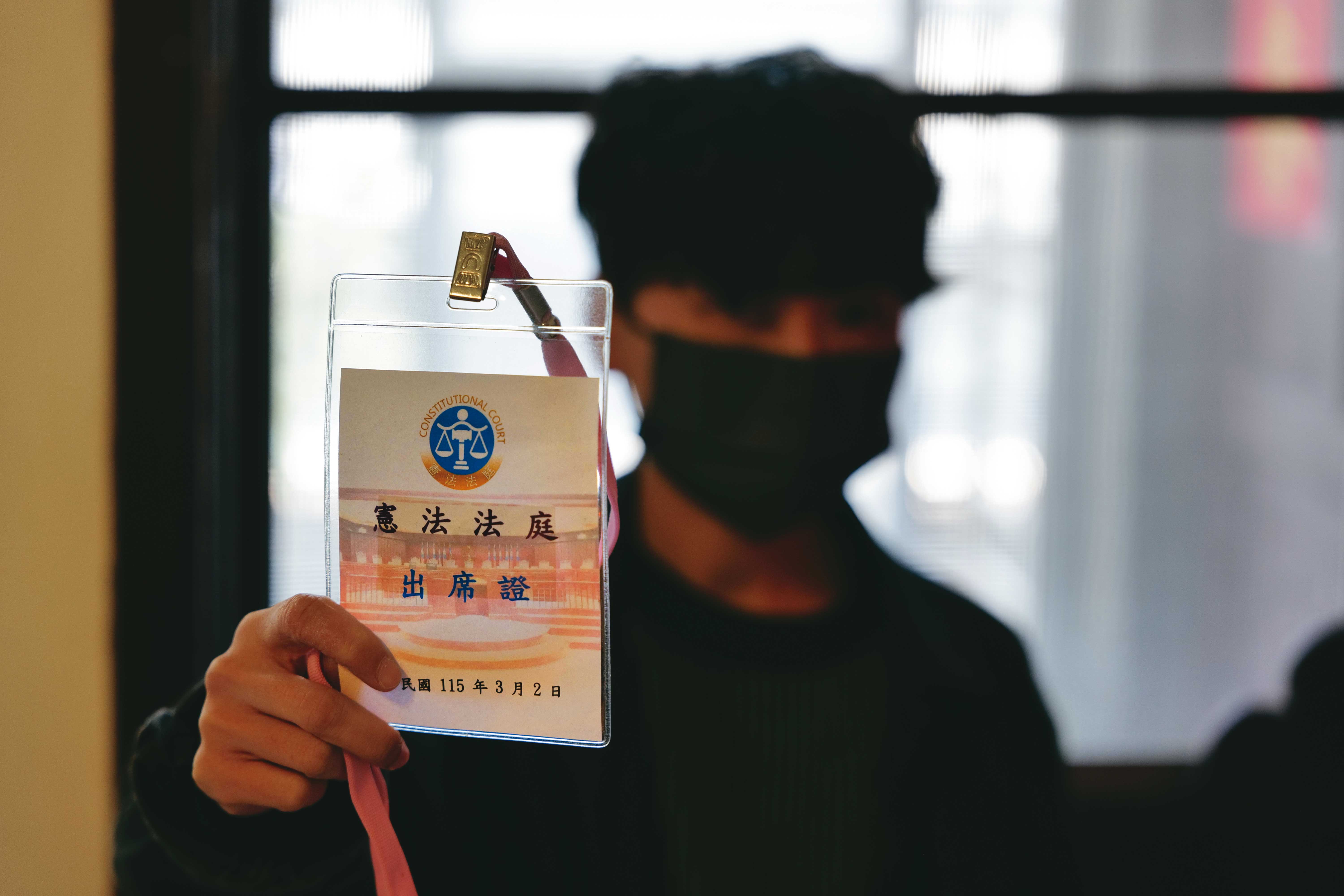 J拿著3月2日憲法法庭不公開說明會的出席證，她正在等待釋憲的結果。