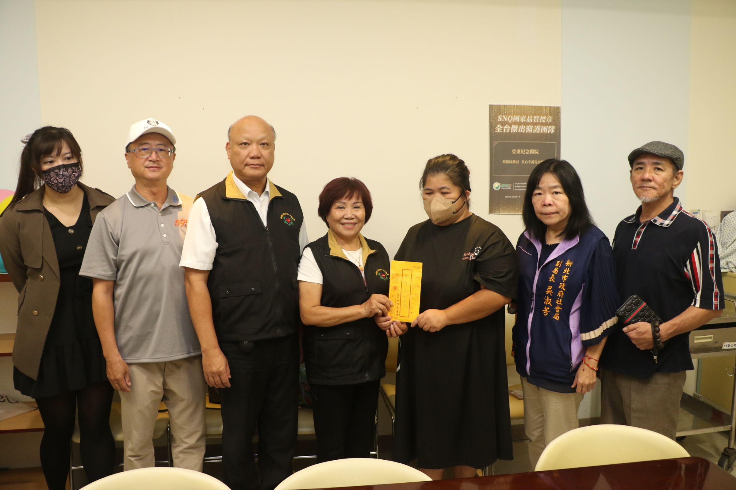中華單協理事長潘承揚（右起）、社會局副局長吳淑芳、吳媽媽、一竹慈善會理事長許品、圓融行善團團長許誥、急難救助會理事長洪守坿和祕書鄭子妤等人一起到醫院探視吳媽媽，並贈急難救助金。（新北市社會局提供）