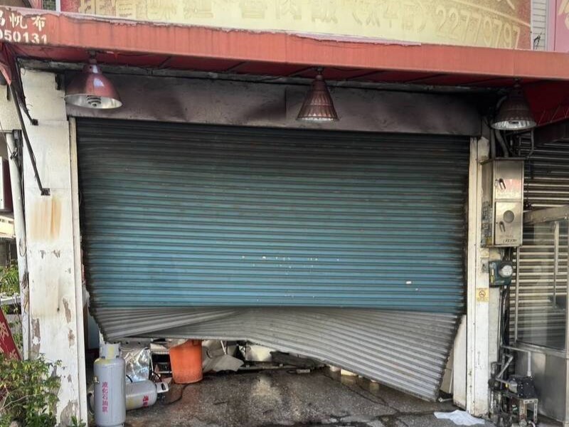 黃姓男子開車低頭撿手機，車輛失控衝撞魚翅肉羹店，鐵捲門嚴重變形。（翻攝畫面）