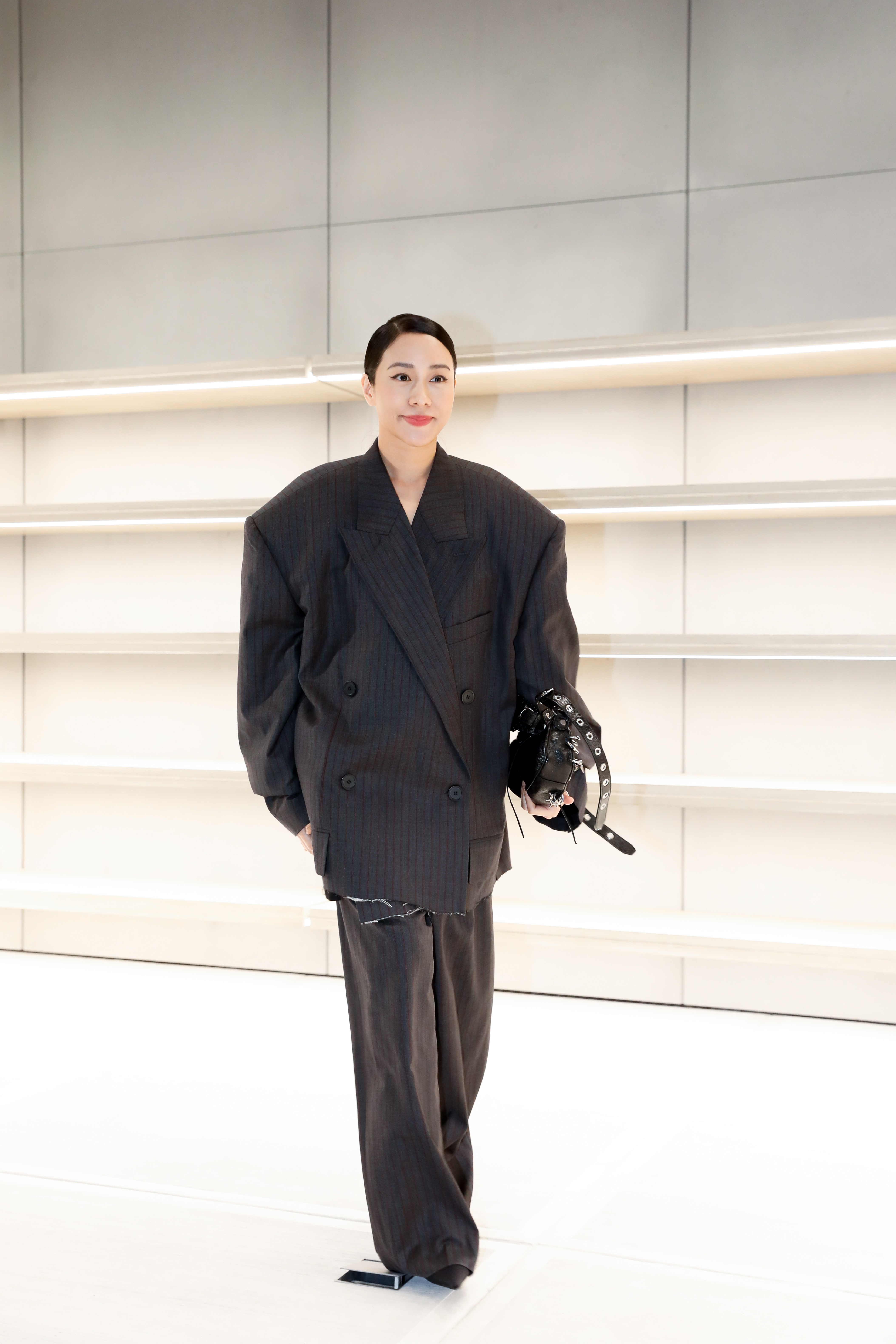 林嘉欣身穿Balenciaga寬鬆版型灰底紅條紋西裝外套(NT$103,800)與同款褲(NT$50,000),搭配劍頭靴(NT$43,100),手拿台北101獨家限定Le Cagole黑色尖刺穿環造型肩下包(NT$105,850)。
