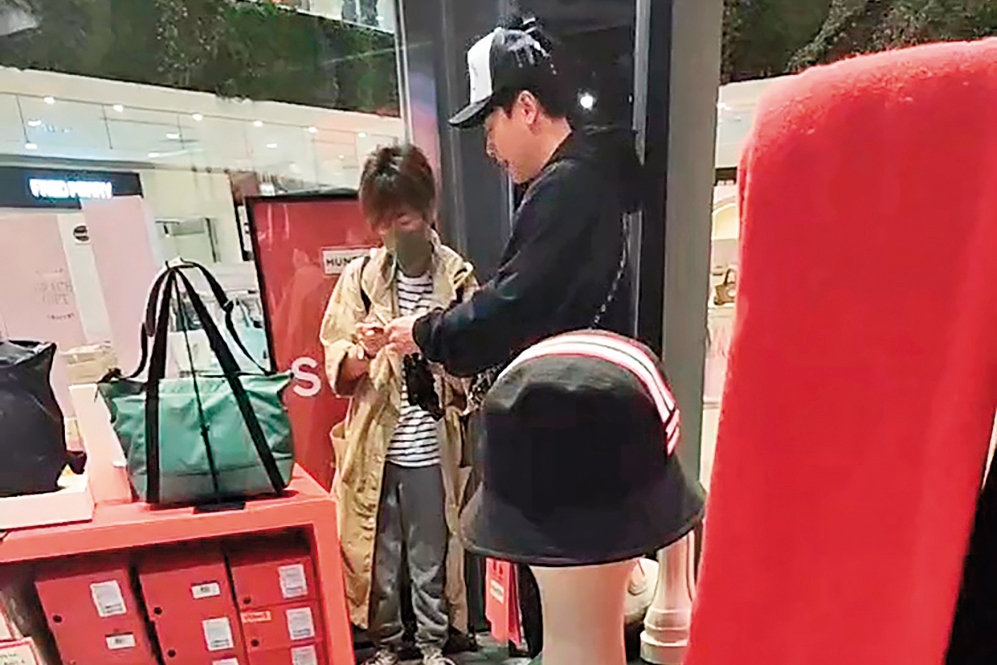 女友人在店內仔細看包,王振復在一旁不時給意見。(讀者提供)