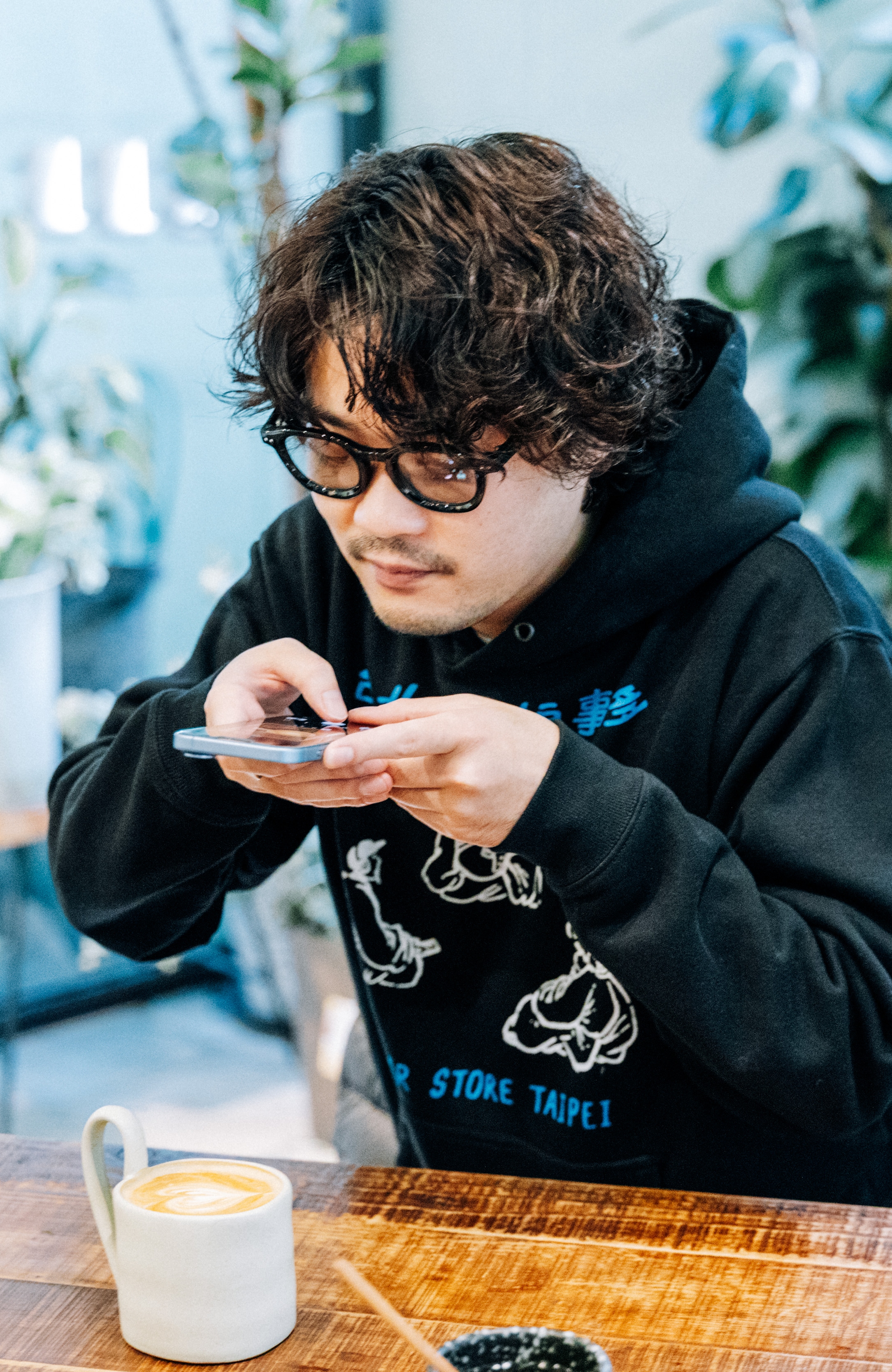鈴木龍也導演一坐下來就拿手機拍咖啡，笑說：「好喜歡台灣，覺得什麼都很新奇有趣。」（佳映娛樂提供）