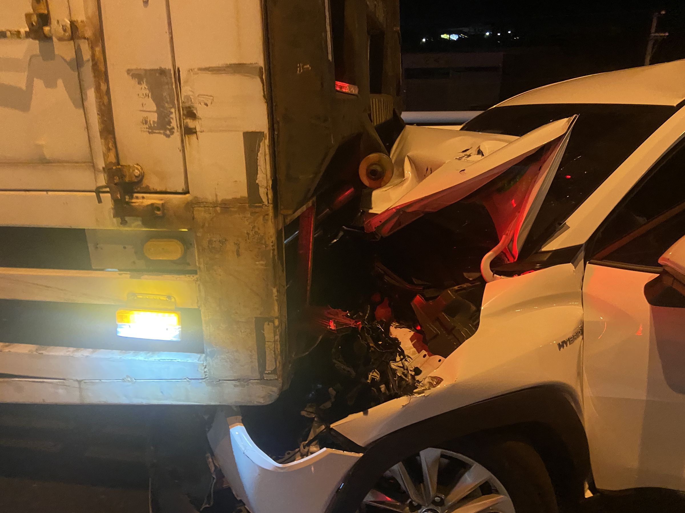 車禍事故中1部轎車被夾在2輛大貨車間，車頭嚴重毀損，駕駛輕傷送醫。（翻攝畫面）