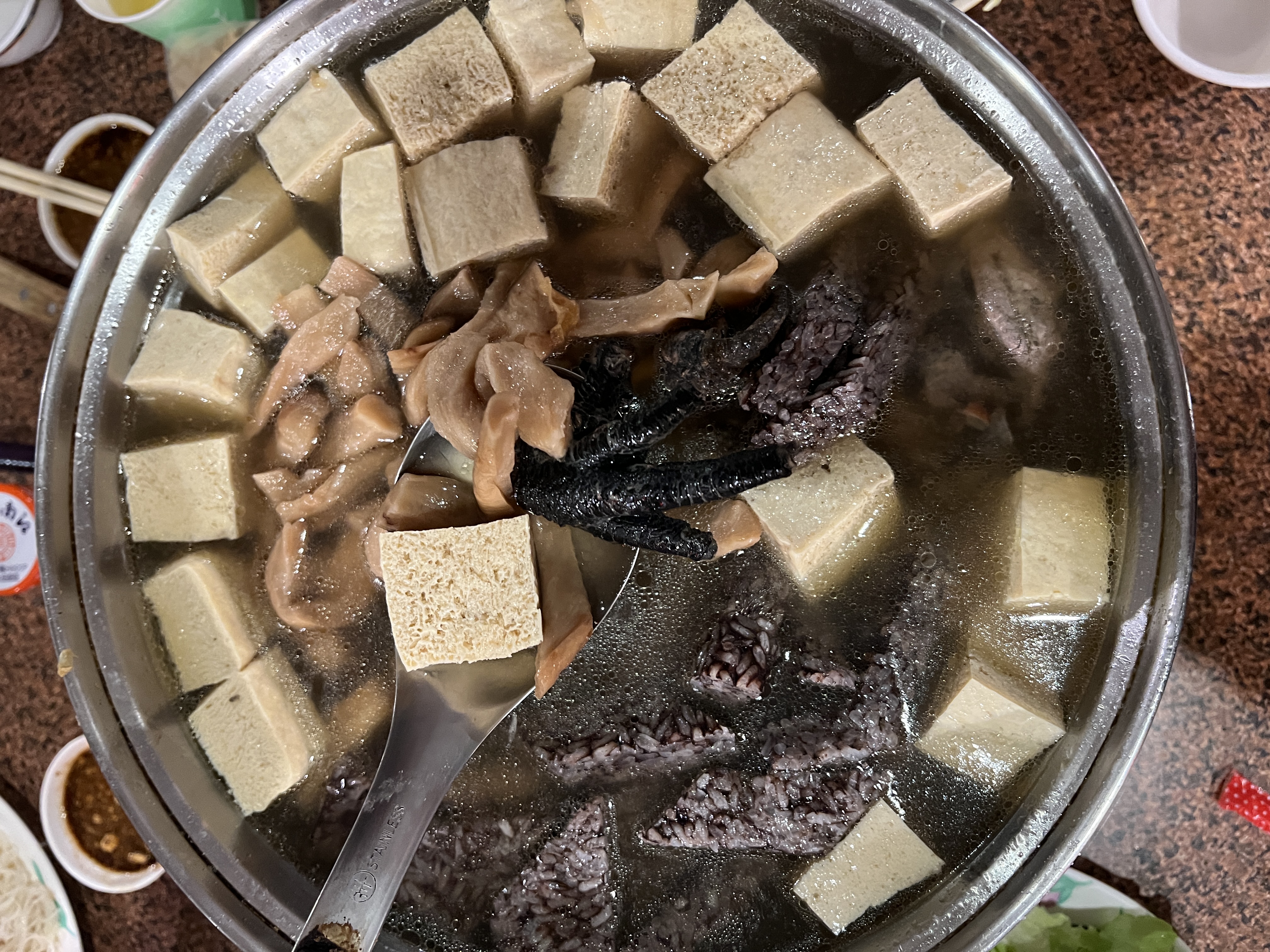滿滿一大鍋的菜脯雞上桌，裡頭有一整隻烏骨雞和大量蘿蔔乾，滾煮之後更有味道。