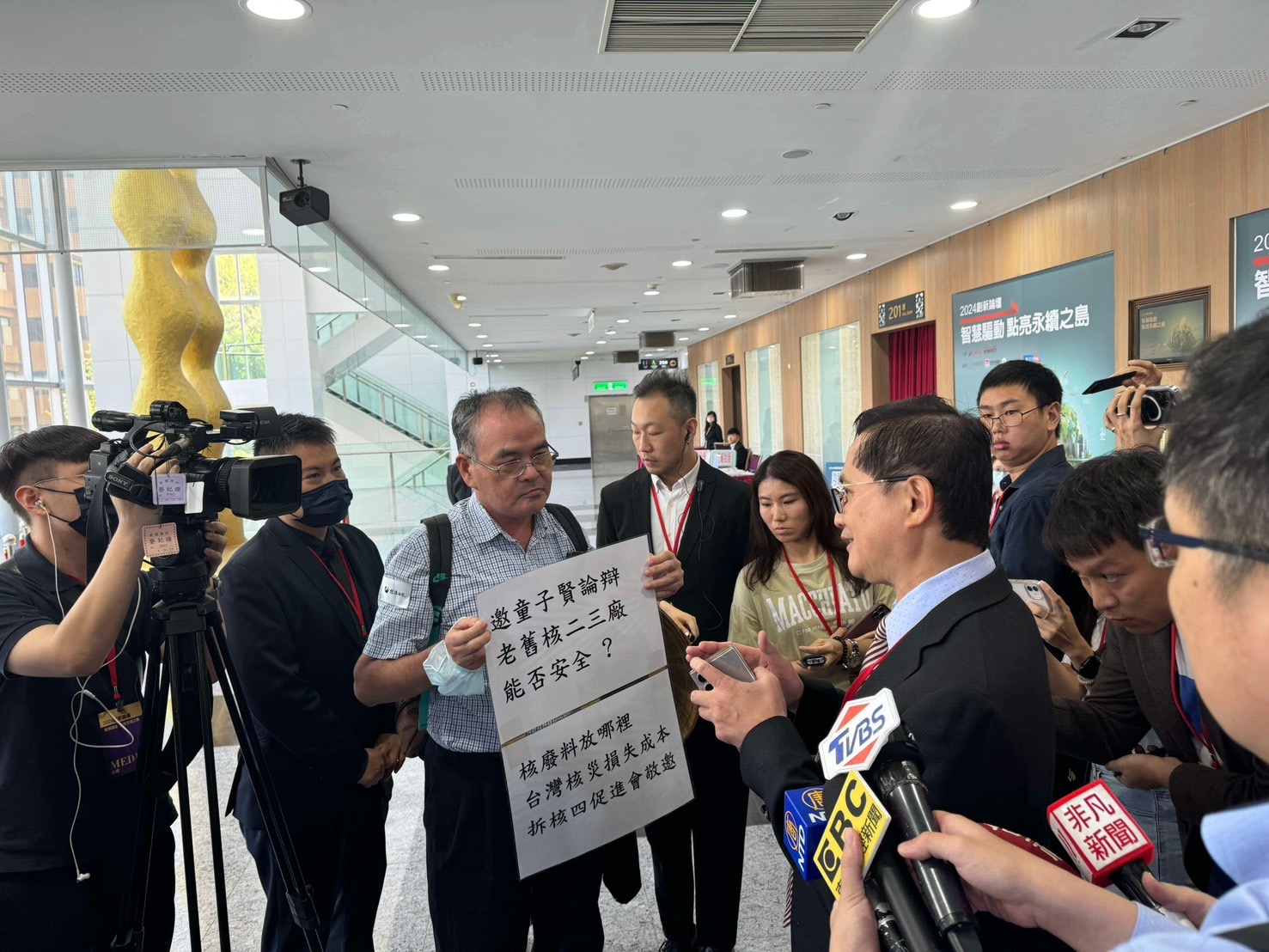 面對反核人士舉牌抗議，童子賢主動上前握手致意。（讀者提供）