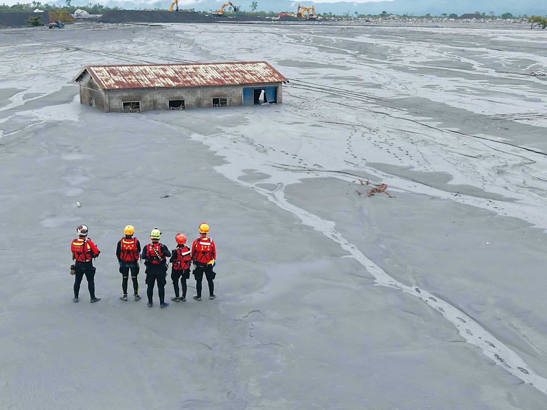 一棟民宅矗立在淤泥中，搜救隊員則持續在附近尋找生還者。（新北市消防局提供）