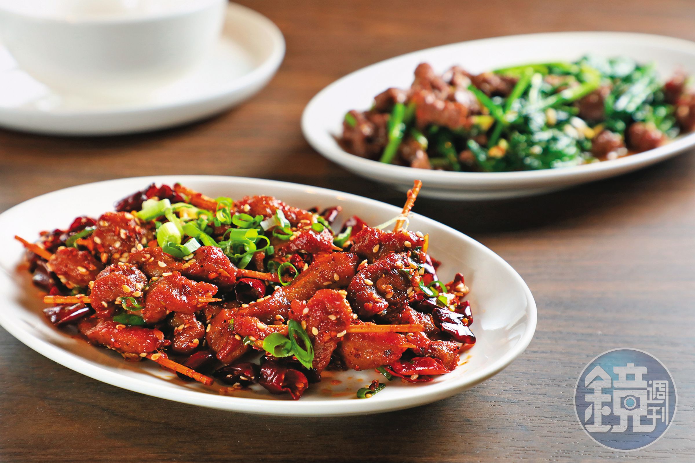 將牛肉醃製入味,用牙籤一根根串起,加入芝麻與祕製辣粉,就成了色香味俱全的「牙籤牛肉」(前,380元/份),後為「芥蘭牛肉」(280元/份)。
