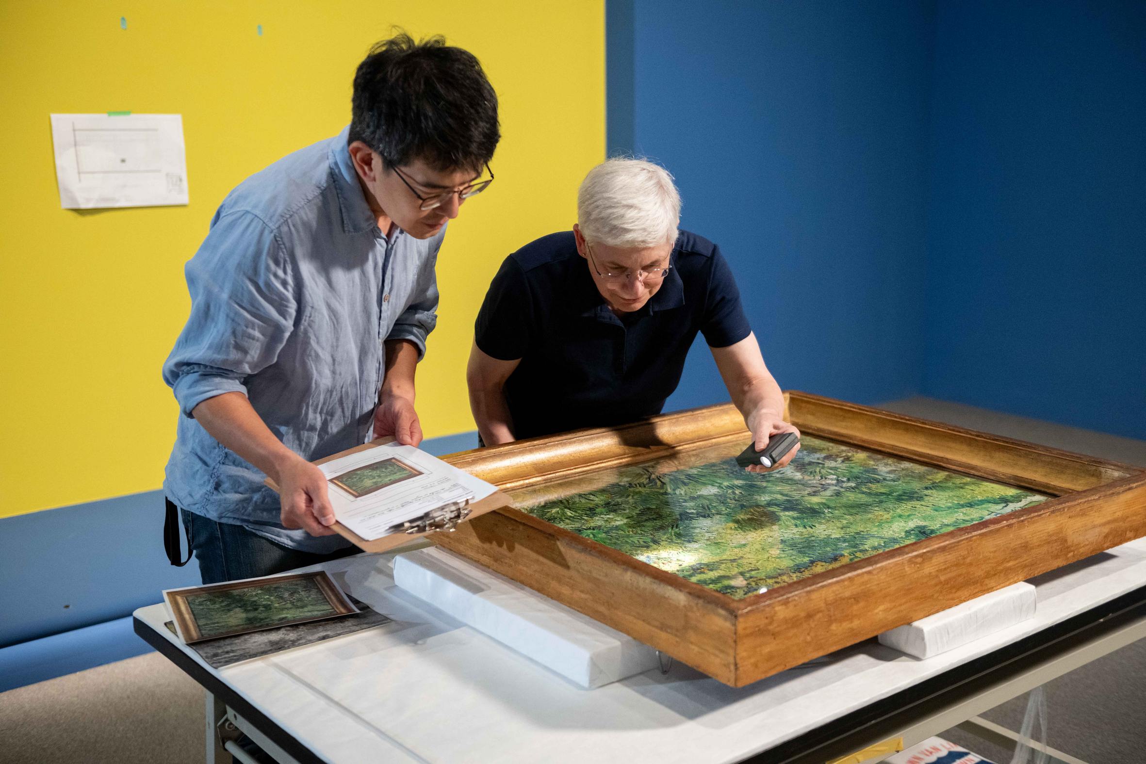 奇美博物館《英國國家藝廊珍藏展》布展過程中，兩館的修復師仔細檢視梵谷的作品〈長草地與蝴蝶〉。（奇美博物館提供）