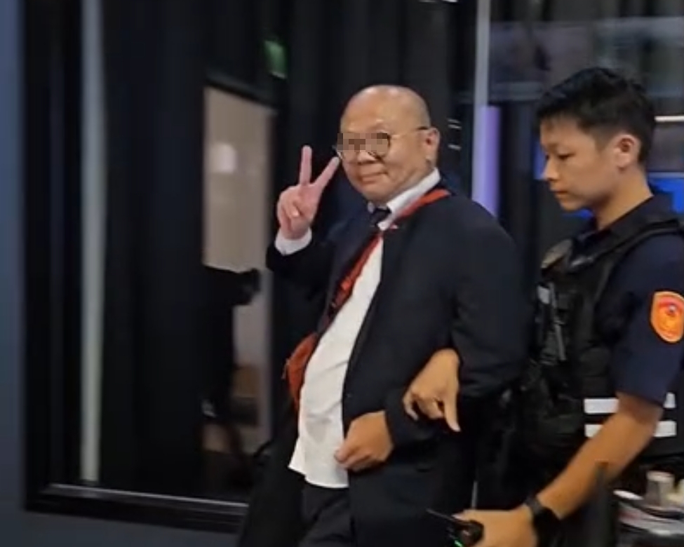 怪男亂創電視台，被警方帶走竟還對鏡頭比「YA」。（翻攝畫面）