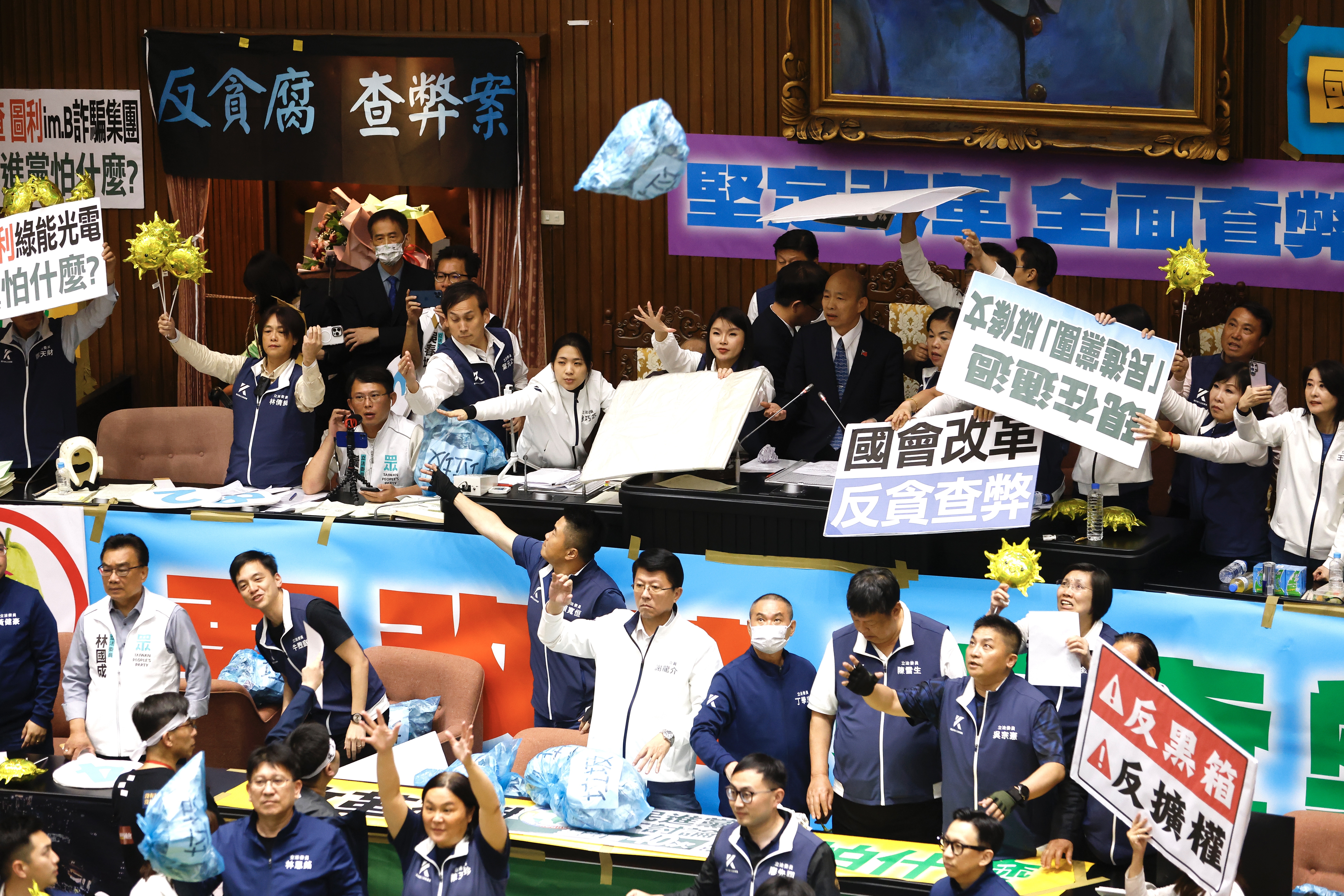 民進黨團朝主席台狂丟「垃圾」，但都被手持太陽造型氣球、高喊「讓陽光照進國會」的國民黨團擋下。