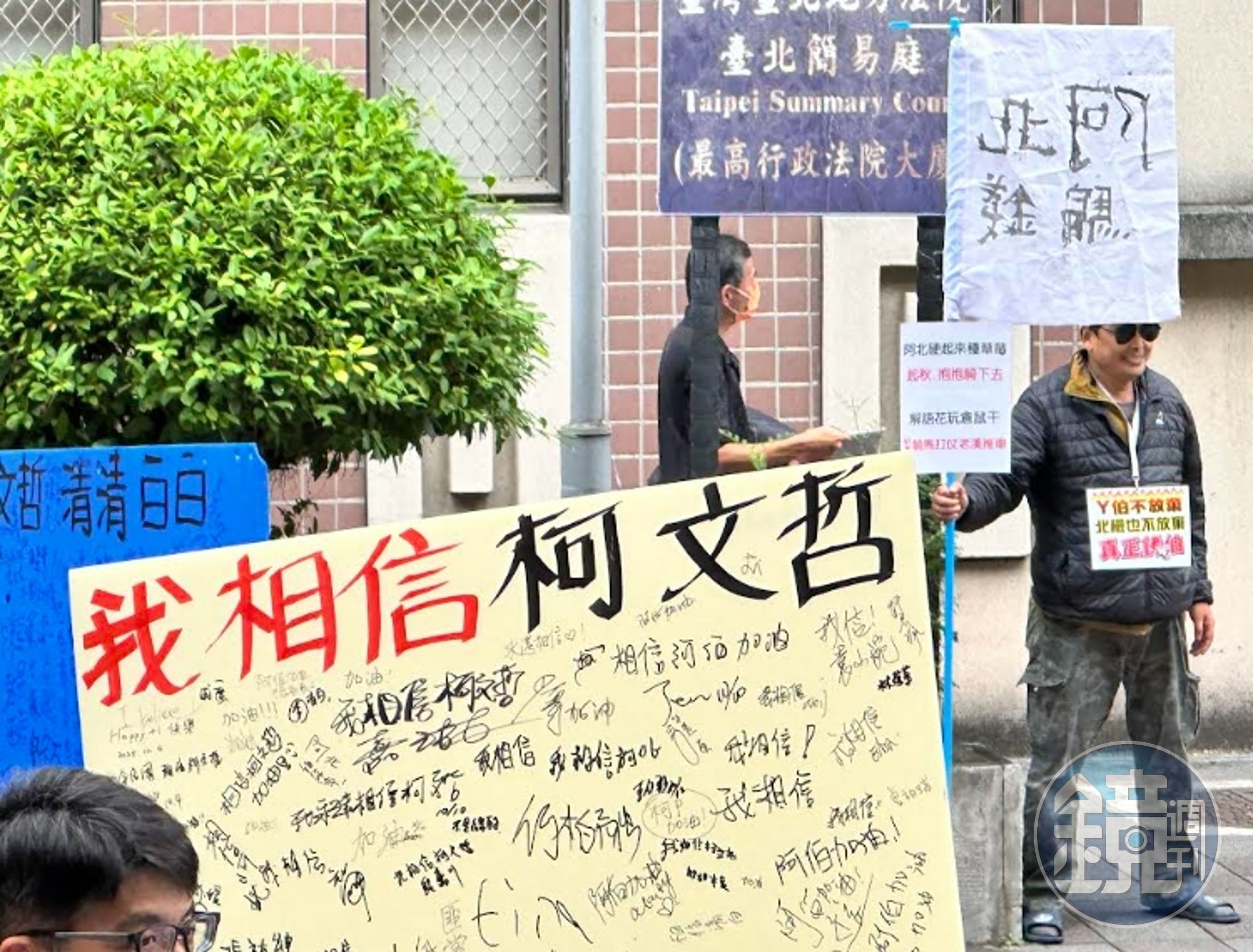 柯文哲的支持者手持「相信柯文哲標語」與對街持「阿北騙錢」的男子較勁。