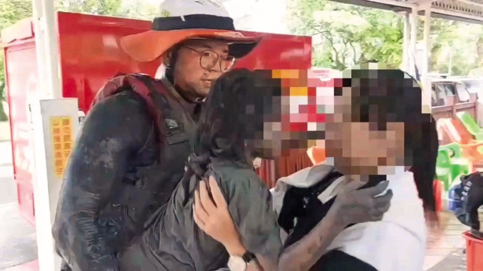 搜救人員將一名滿身泥沙的小女孩（中）抱離災區，送往臨時收容中心，她在洪流後倖存畫面，令在場救難隊與鄉親一度哽咽。（屏東縣消防局提供）