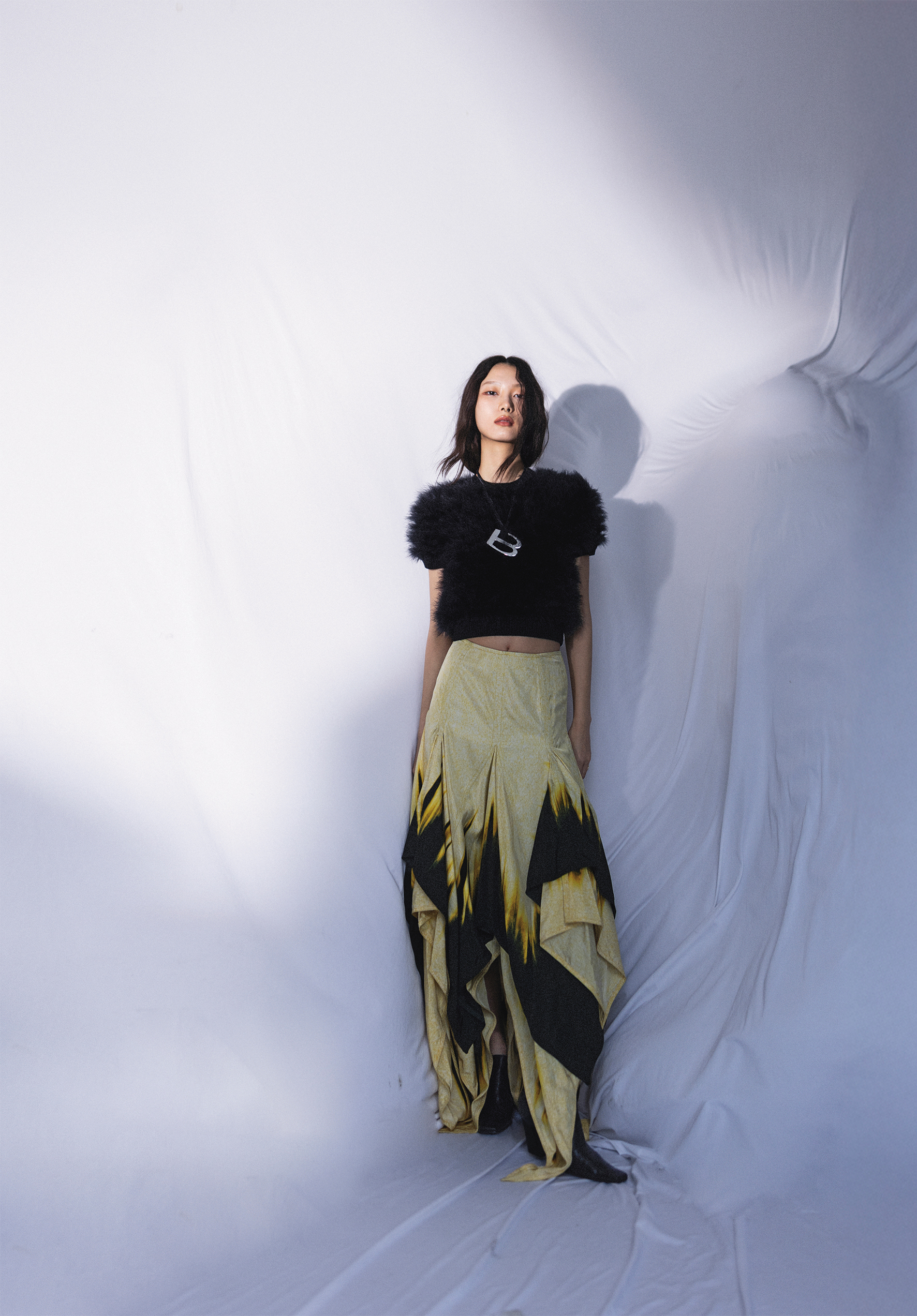 黑色羊毛上衣飾以羽毛細節 價格店洽by PRADA／印花休閒裙NT$150,800 by BOTTEGA VENETA／LEWIS皮革休閒鞋 價格店洽by BOTTEGA VENETA／CRAZY B項鍊 價格店洽by BALENCIAGA