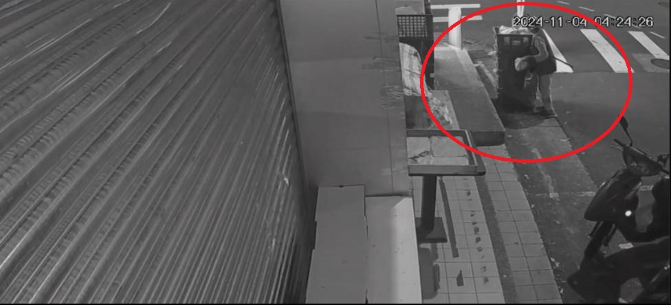 婦人（紅圈）趁清晨至水果店門口貨籃拿取水果，到案後稱是為了餵養果子狸。（翻攝畫面）