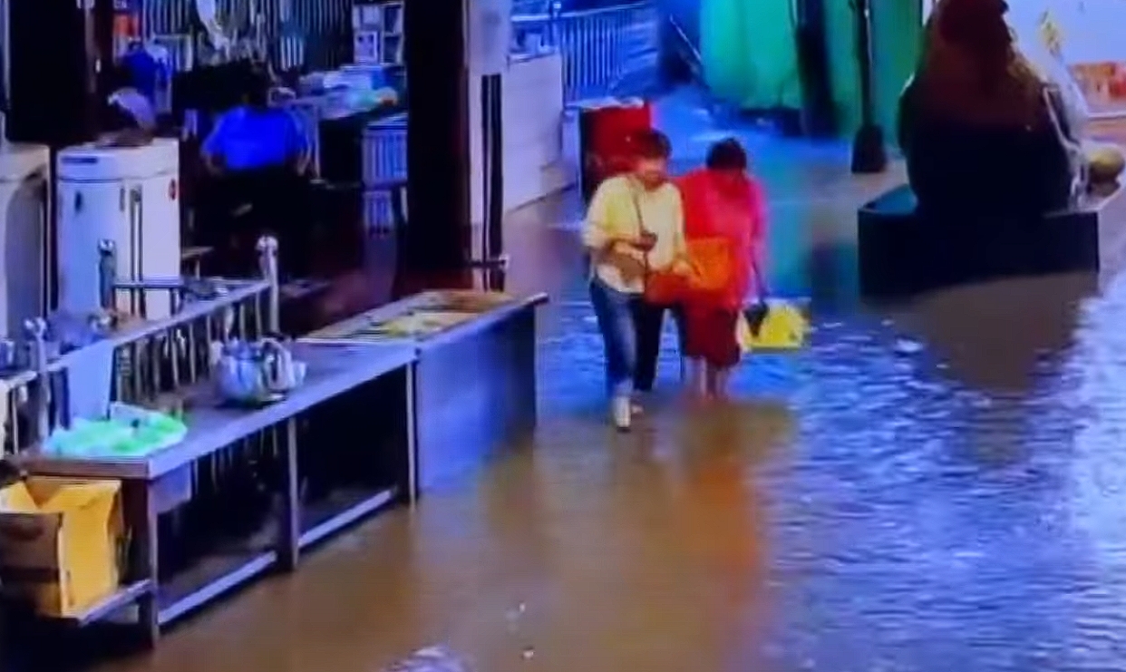 南投竹山紫南宮9日暴雨成災，水淹小腿肚，要摸金雞母求財的民眾只能涉水前進。（翻攝畫面）