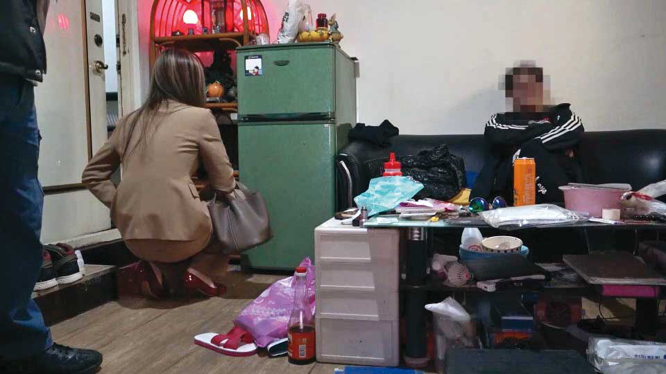 檢警去年底到張男租屋處搜索，張男（右）被要求坐在椅子上等候。（翻攝畫面）